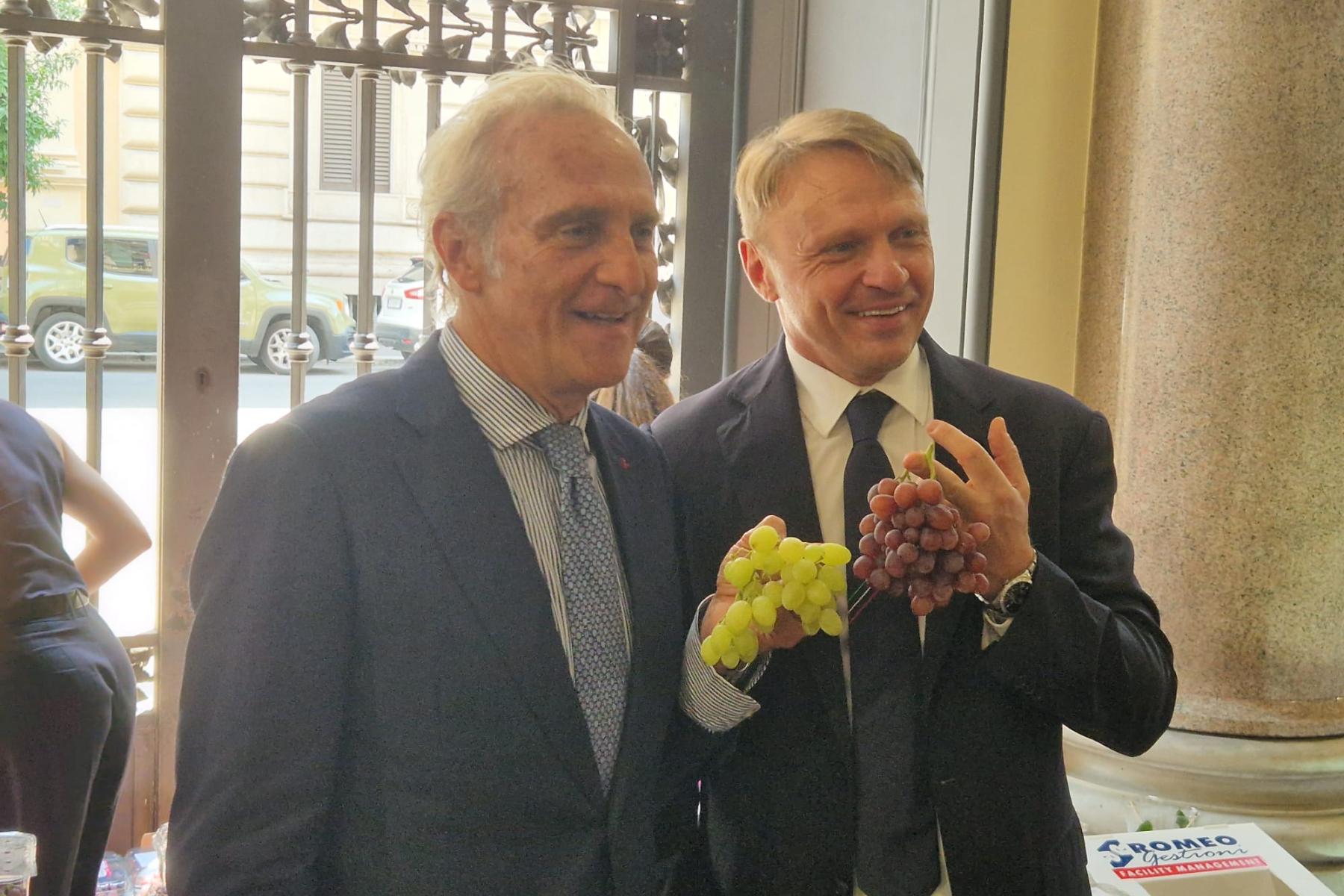 Fruitimprese-Präsident Marco Salvi und Landwirtschaftsminister Francesco Lollobrigida halten je eine Traubenrispe in der Hand