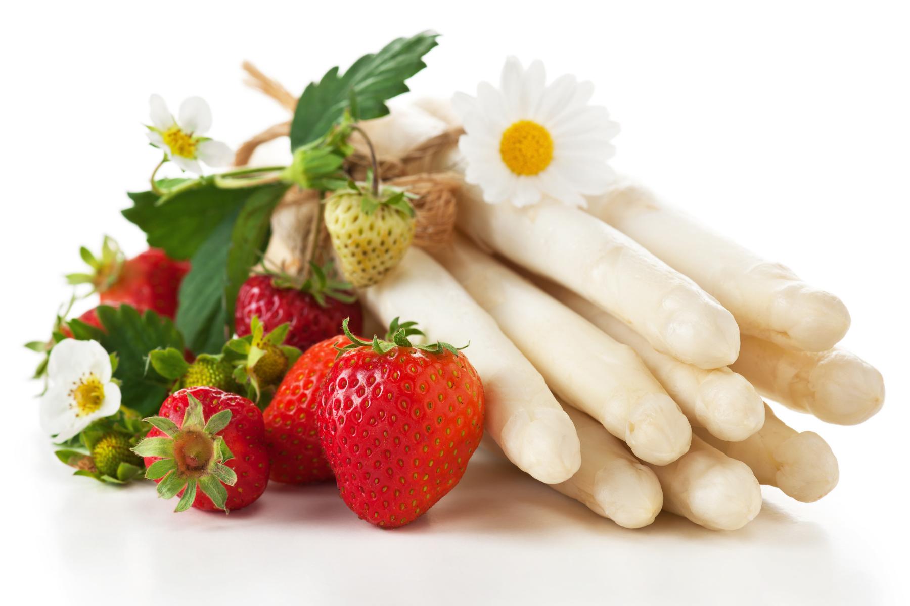Weißer Spargel und frische Erdbeeren mit grünen Blättern und weißen Blüten