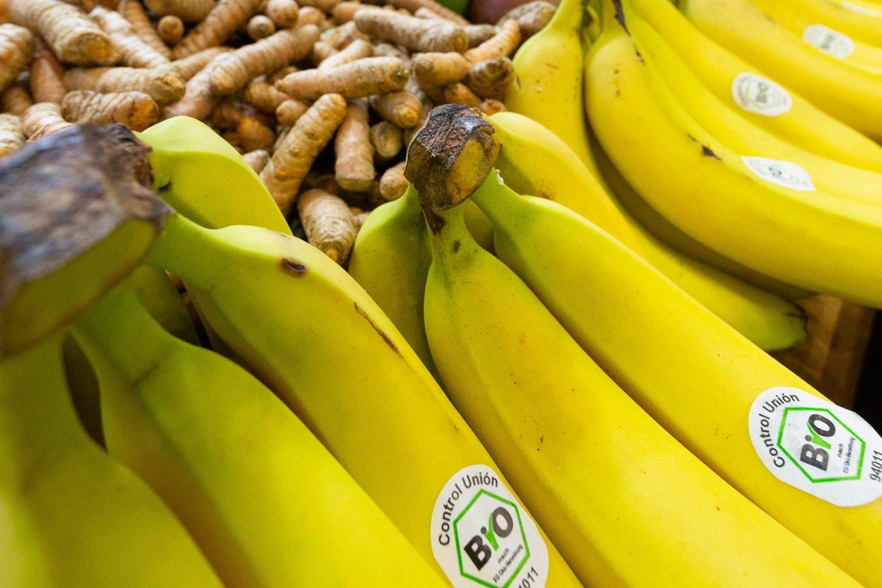 Bio-Bananen auf einem Regal, Mangos im Hintergrund