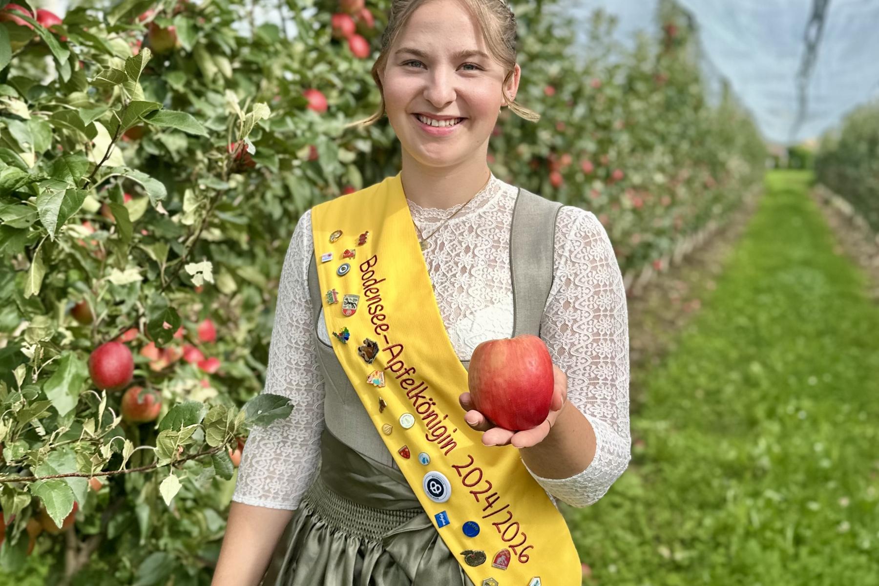 Apfelkönigin Emelie Witzigmann mit Apfel in der Hand in einer Apfelplantage