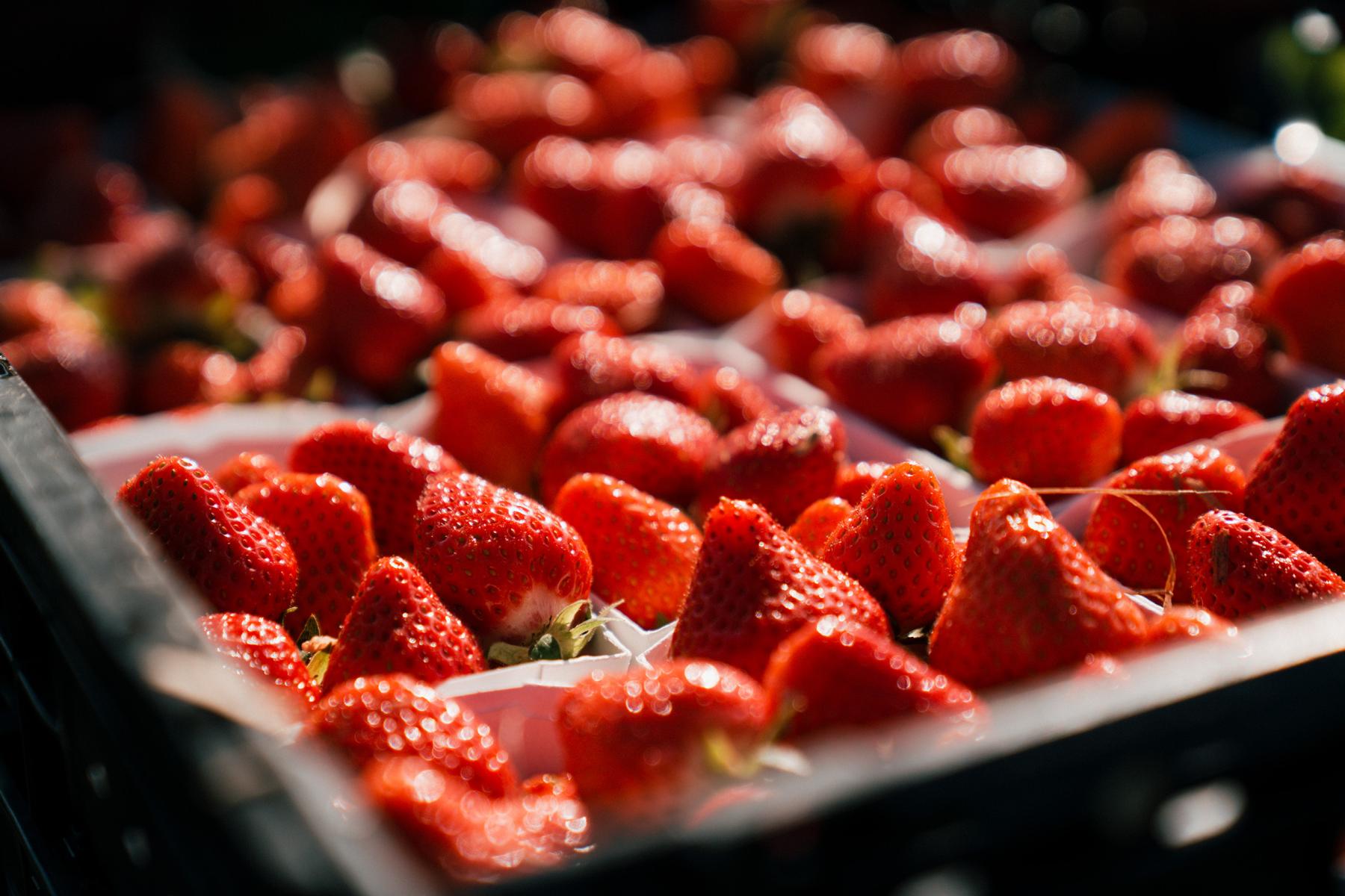 Nahaufnahme von mehreren roten Erdbeeren in einer schwarzen Kunststoffkiste