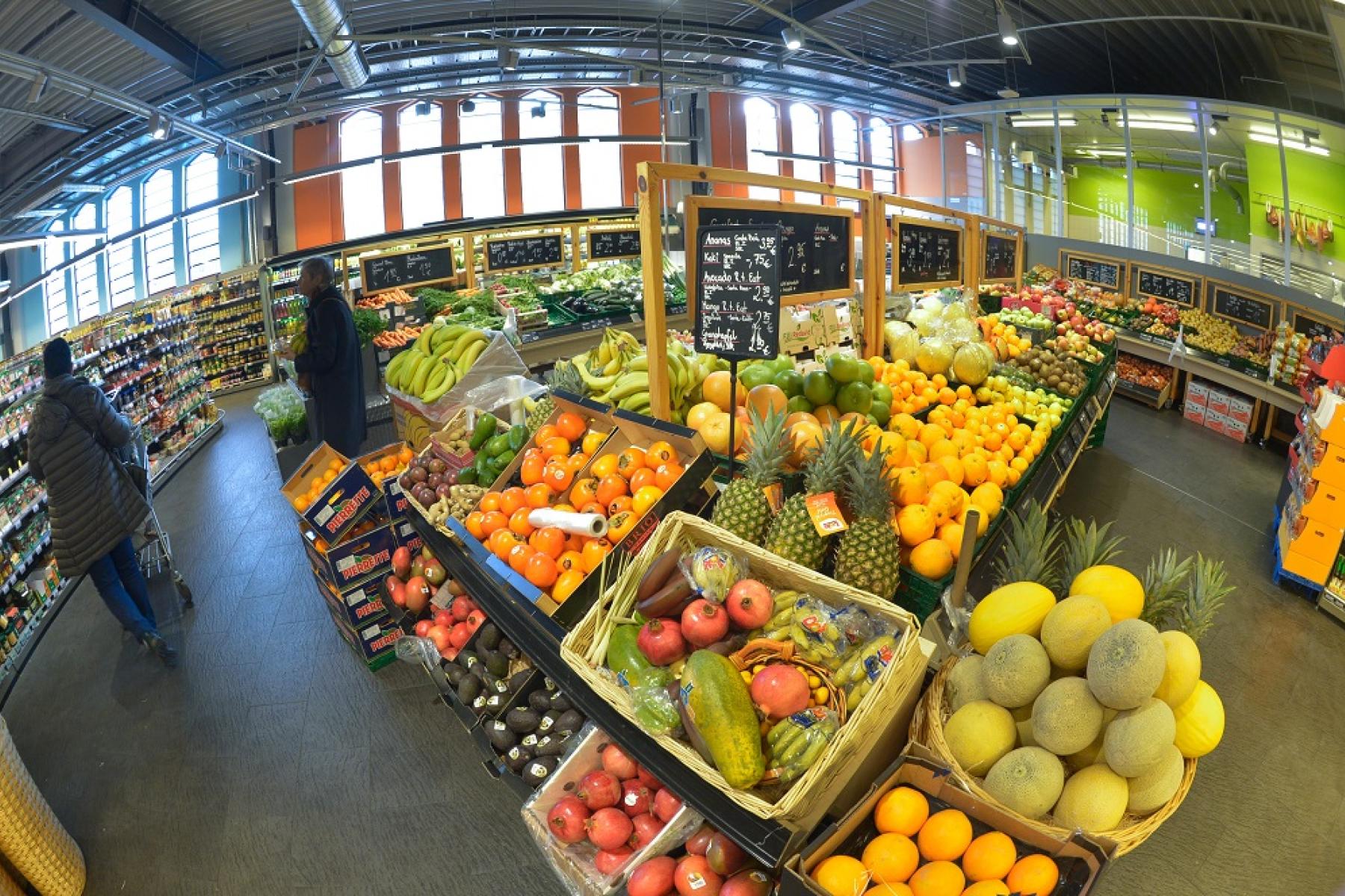 Obst- und Gemüseabteilung im LEH mit verschiedenen Früchten wie Bananen, Orangen, Melonen und Ananas