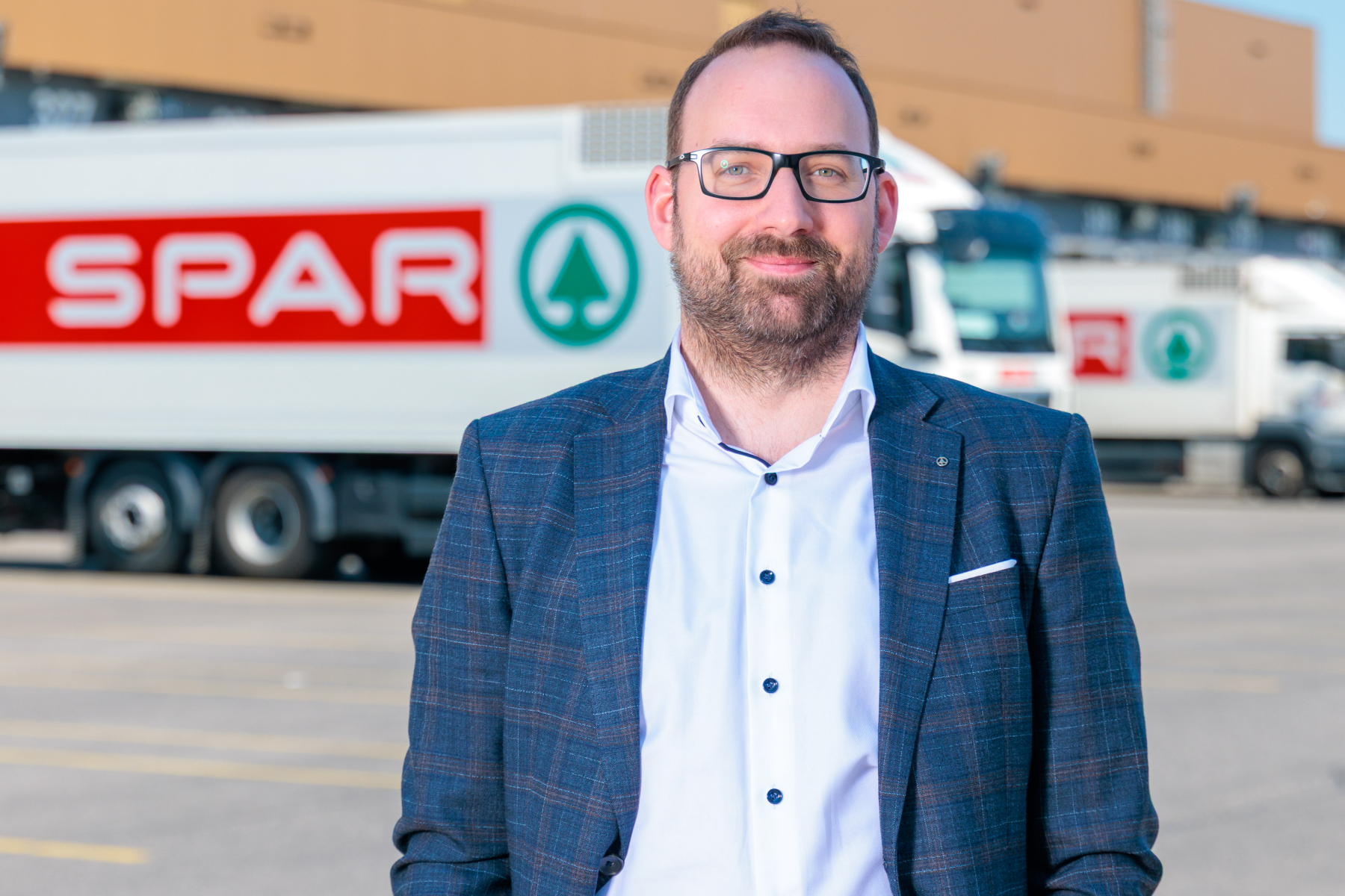 Patrick Hörmann steht vor einem SPAR-LKW auf einem Parkplatz