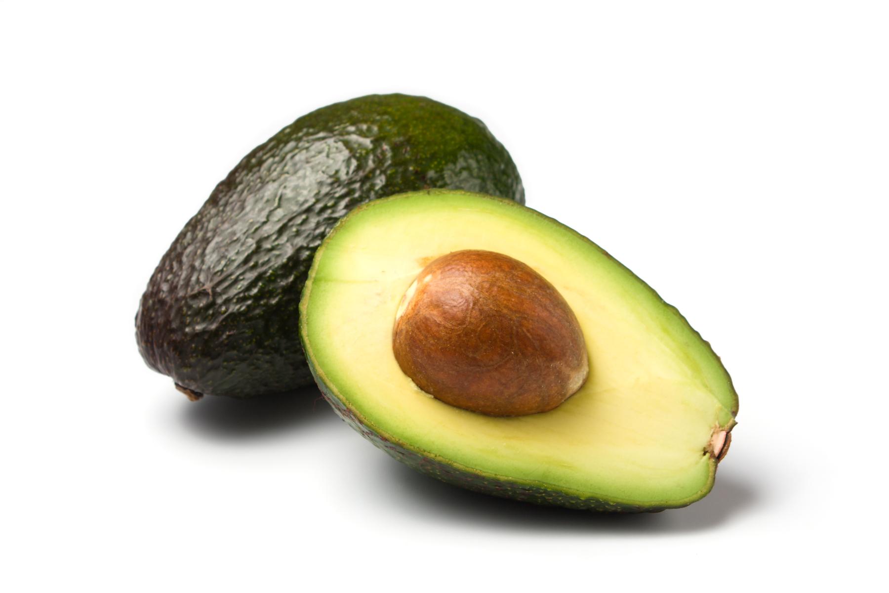 Eine ganze und eine halbe Avocado mit einem sichtbaren Kern in der Mitte.