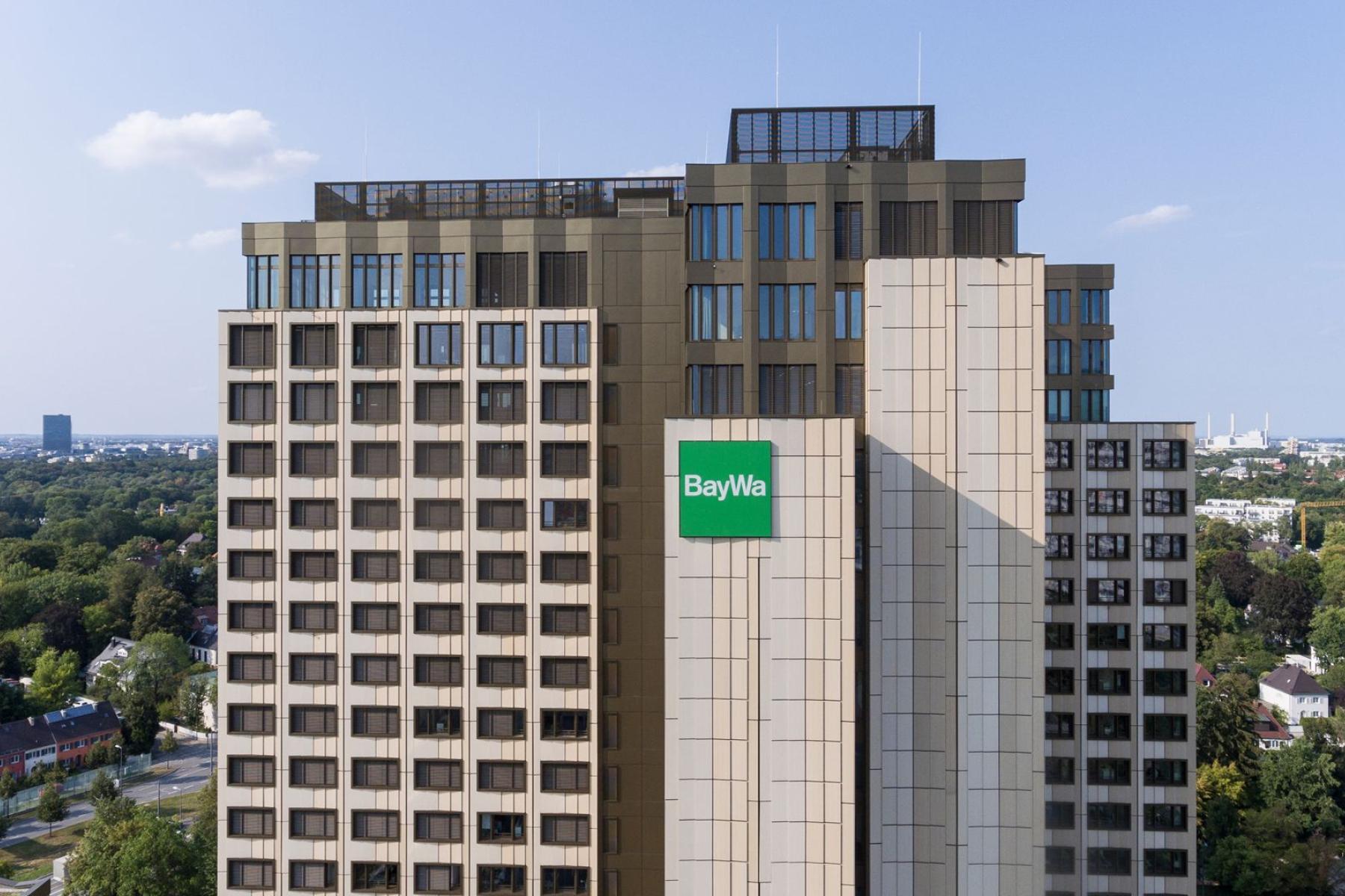 Hauptsitz der BayWa AG, mehrstöckiges Bürogebäude mit grünem BayWa-Logo an der Fassade, umgeben von Bäumen und Stadtlandschaft