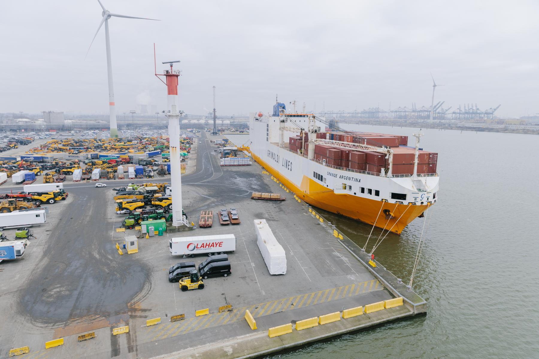 Großes Frachtschiff der Reederei Grimaldi Lines am Dock im Hafen von Antwerpen-Brügge, umgeben von Containern und Hafenanlagen