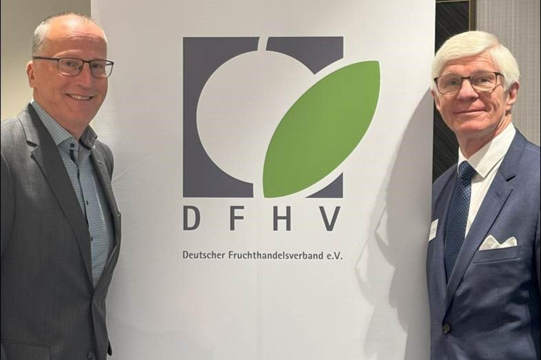 Dieter Krauß und Jürgen Bruch stehen neben einem Banner des Deutschen Fruchthandelsverbands e.V. mit einem grünen Blatt und den Buchstaben 'DFHV'.