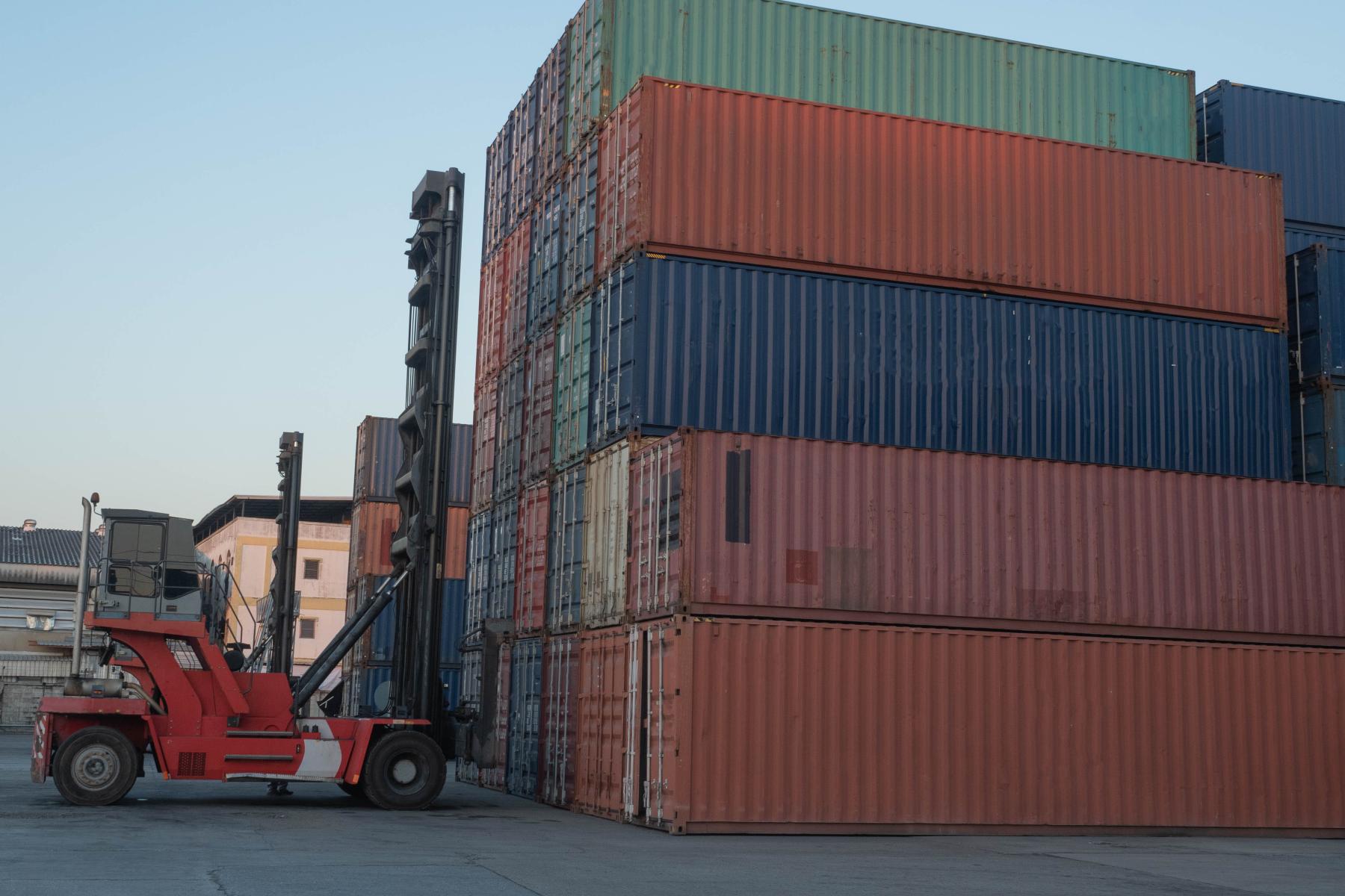 Gabelstapler hebt Container in einem Lager mit gestapelten Frachtcontainern