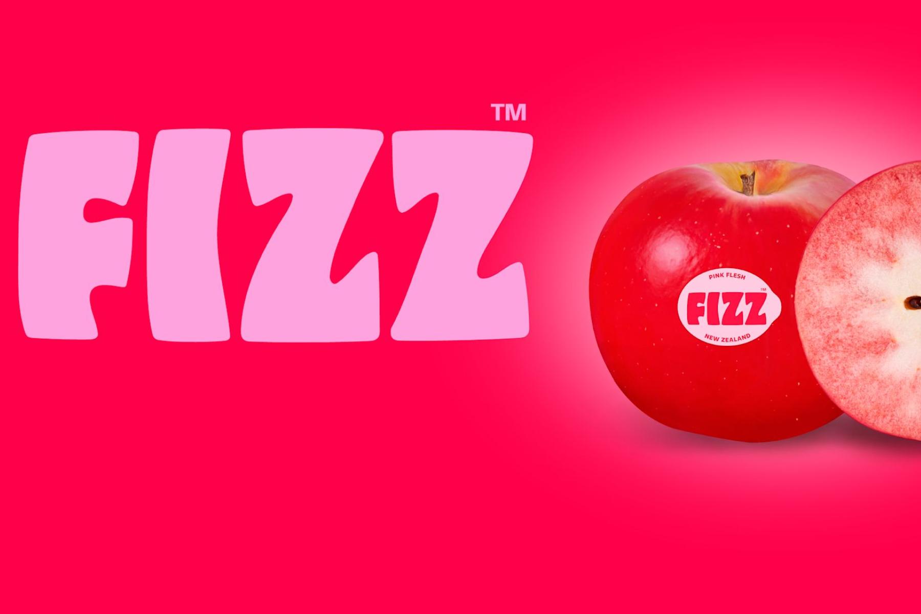 Markenname 'FIZZ' in pinker Schrift auf rotem Hintergrund neben einem halbierten, rotfleischigen Apfel mit sichtbaren Kernen