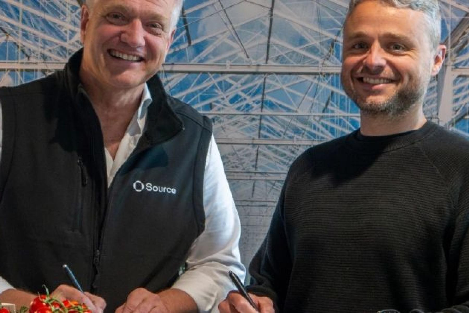 Jelte van Kammen, Generaldirektor von Harvest House, trägt eine schwarze Weste mit Source-Logo, neben Rien Kamman, CEO von Source.ag, in einem Gewächshaus