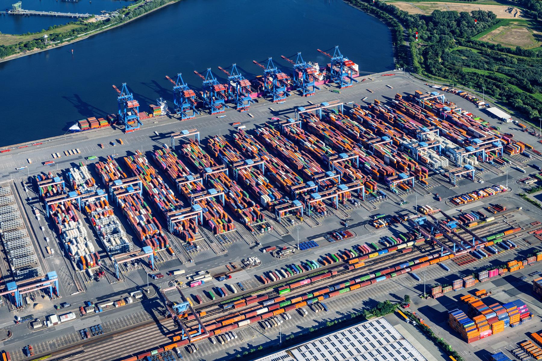 Luftaufnahme des Altenwerder Hafens in Hamburg mit zahlreichen Containern und Kranen. Container sind in verschiedenen Farben angeordnet.
