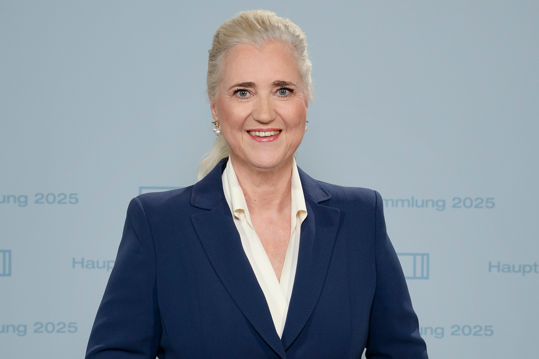 HHLA-CEO Angela Titzrath stehend vor einem Hintergrund mit dem Schriftzug 'Hauptversammlung 2025'