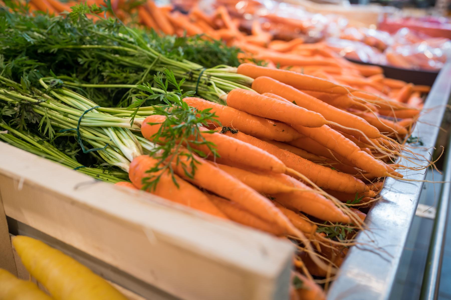 Frische orangefarbene Karotten mit grünen Blättern in einer Holzkiste