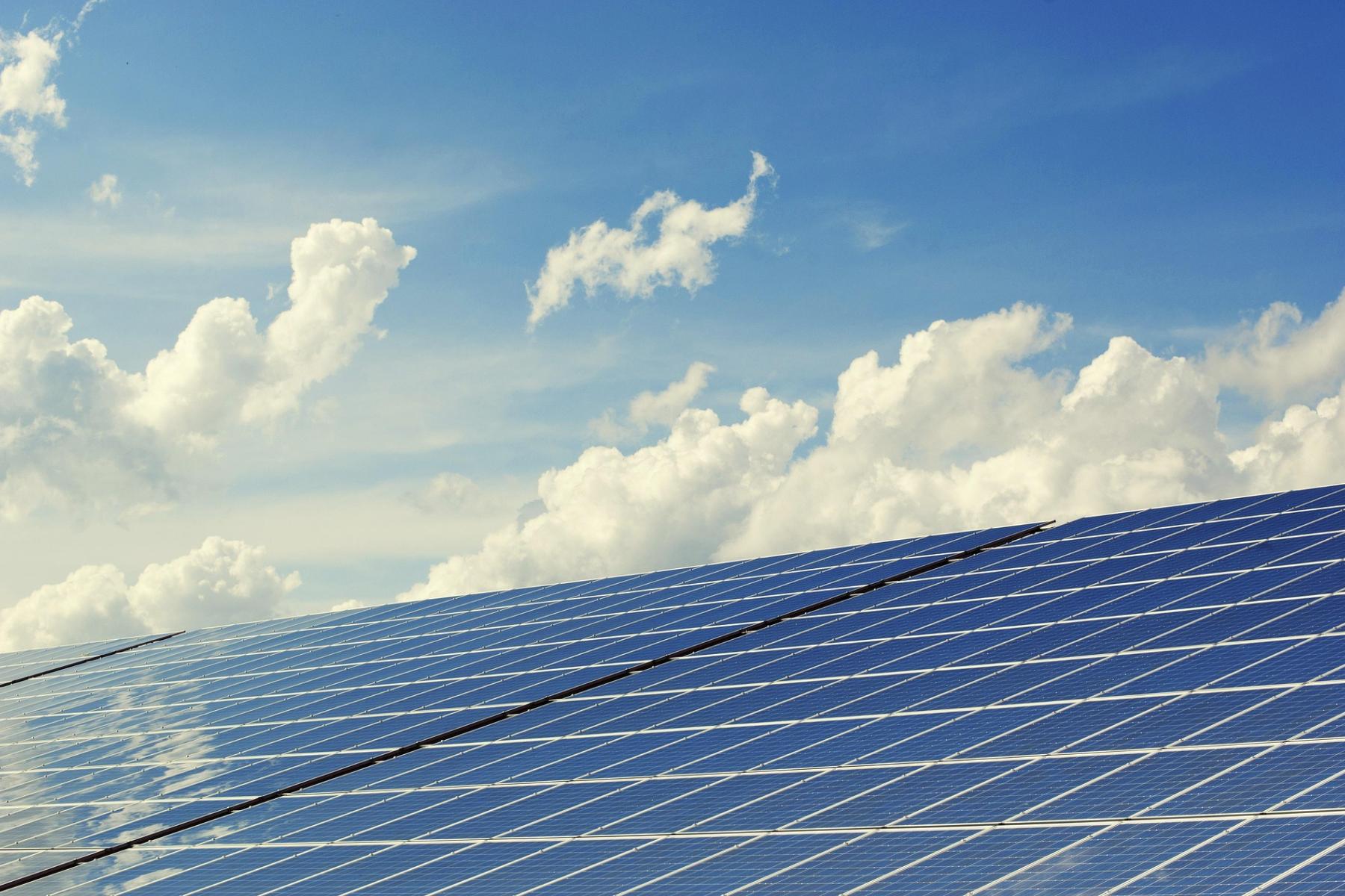Solarmodule auf einem Dach unter blauem Himmel mit weißen Wolken
