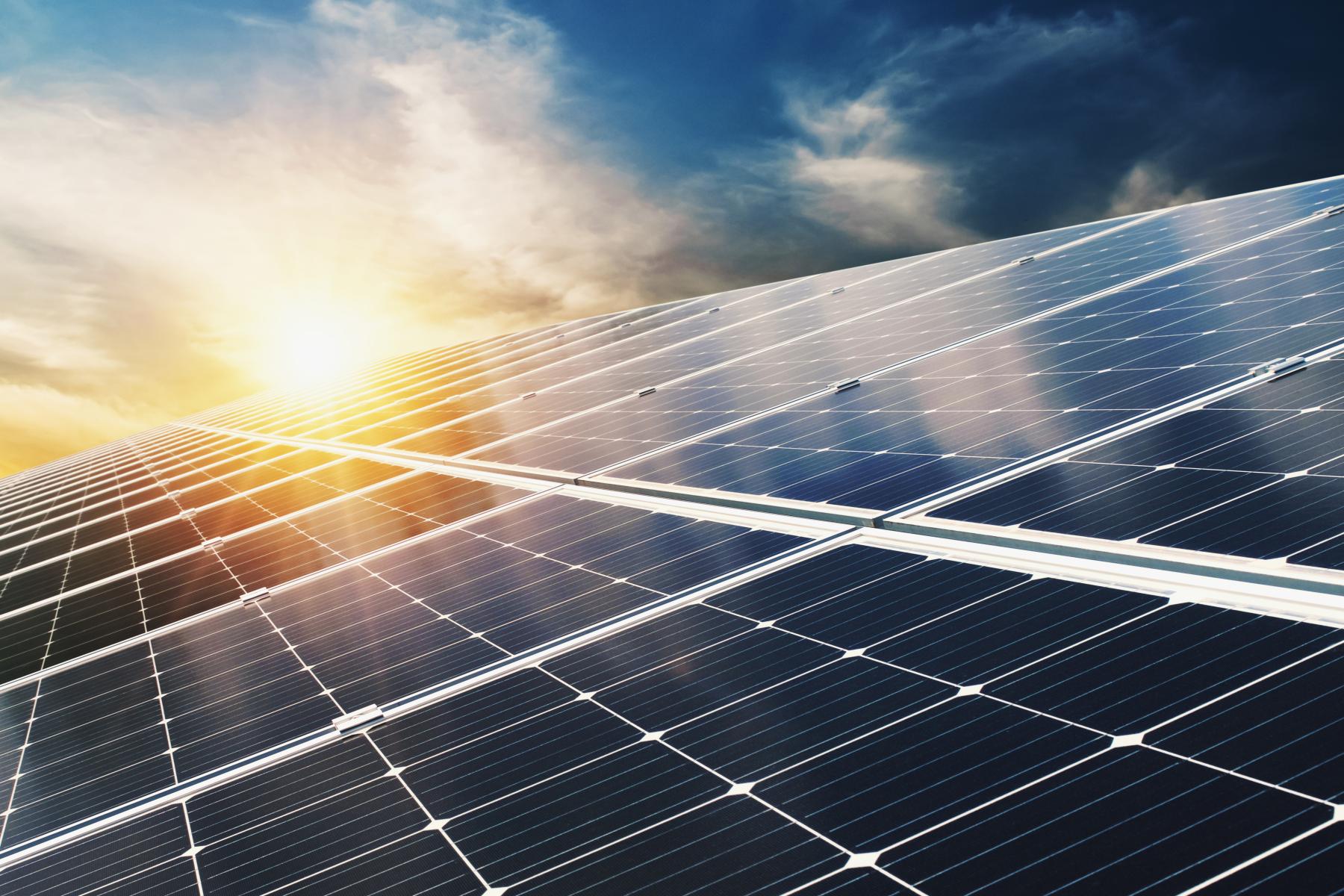 Solarmodule auf einem Dach bei Sonnenuntergang mit teilweise bewölktem Himmel