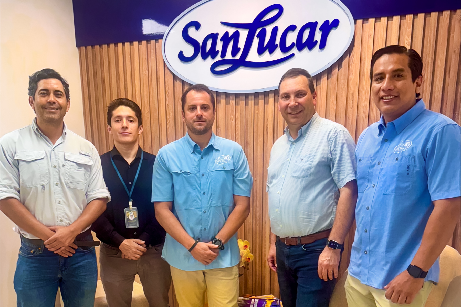Vertreter von SanLucar und Sun World stehen vor einem SanLucar-Logo an einer Holzpaneelwand