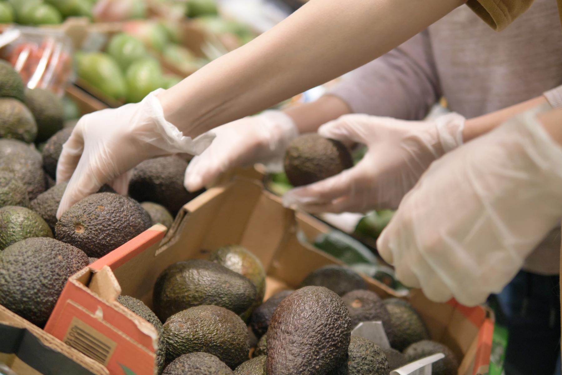 Hand greift nach Avocados in Kisten