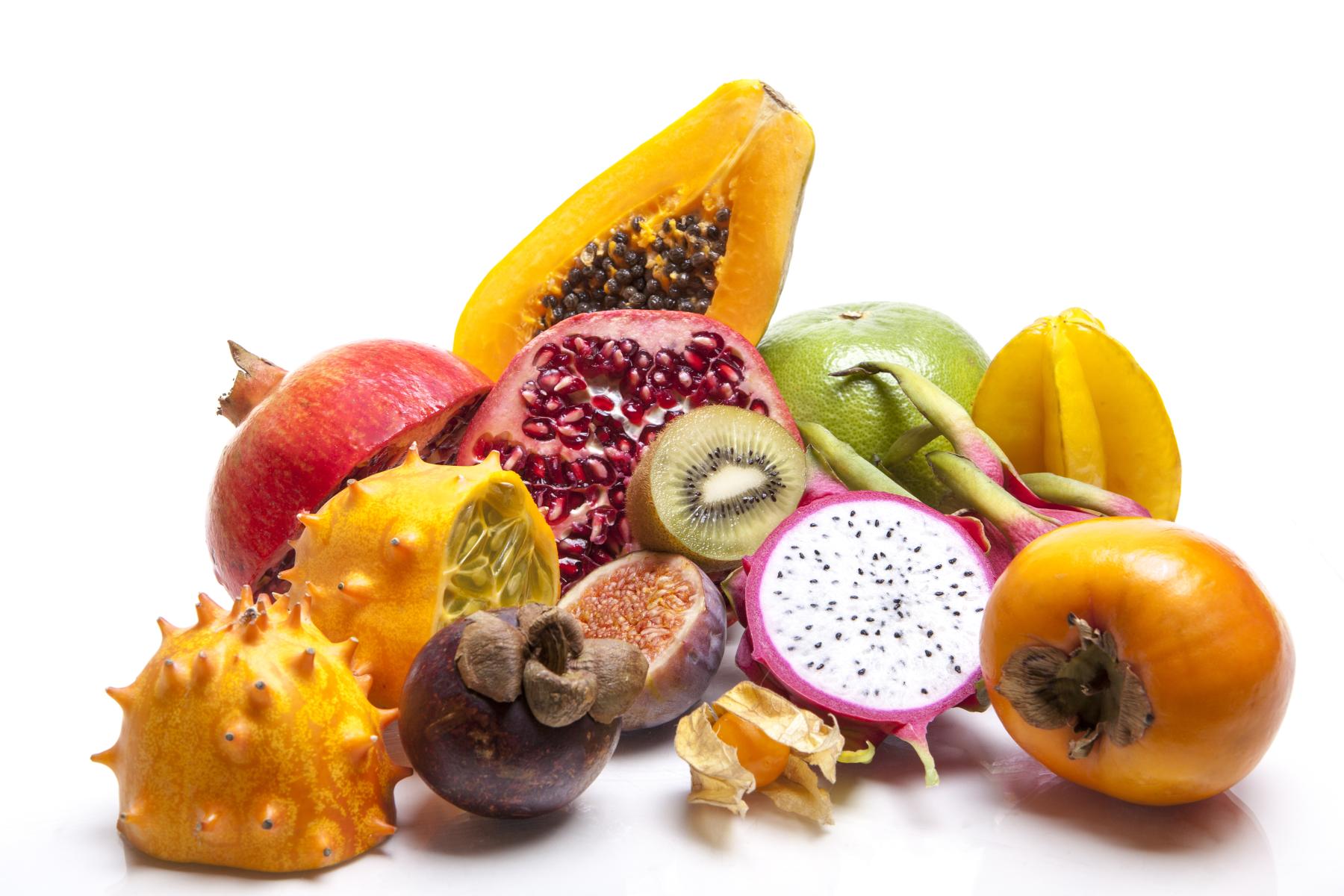 Eine Anordnung verschiedener exotischer Früchte, darunter: Papaya, Granatapfel, Kiwi, Drachenfrucht, Mangostan, Kiwano, Persimone