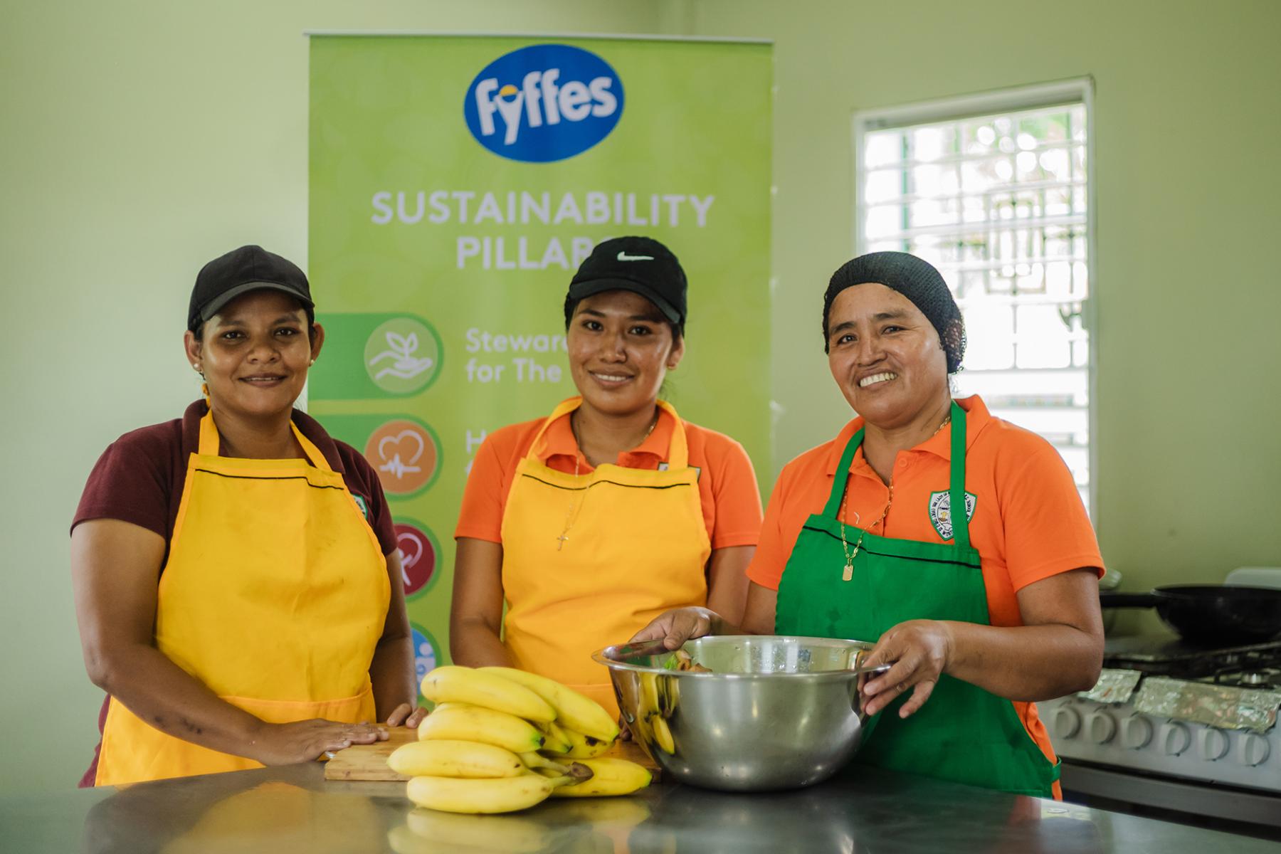 Drei Frauen mit Schürze, Schüssel und Bananen