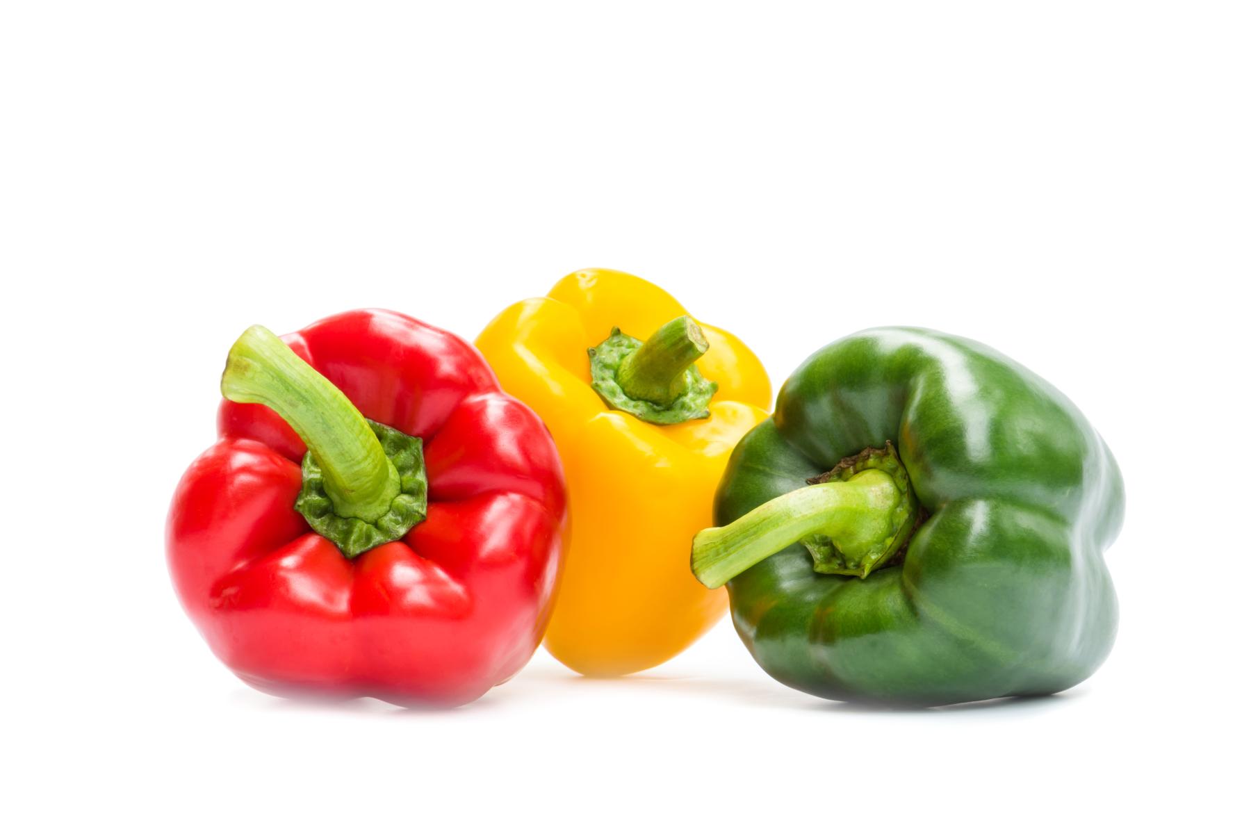 Drei Paprika: eine rote, eine gelbe und eine grüne, in einer leicht versetzten Anordnung. Die Paprika haben glatte Oberflächen und frische Stiele.