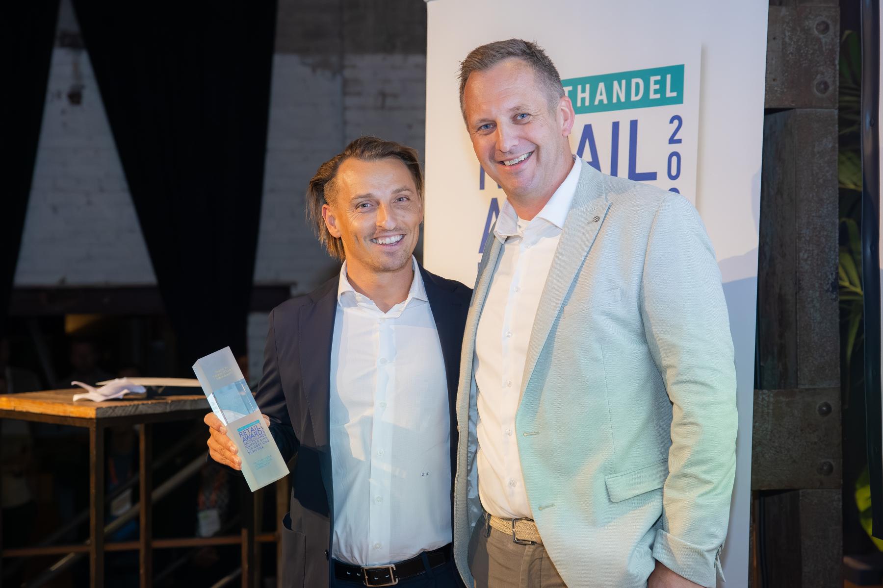 Christoph Stricker (links) von der EDEKA ZENTRALE Stiftung & Co. KG nimmt den Retail Award 2025 von Laudator Michael Rachul (SanLucar) entgegen. Beide stehen lächelnd nebeneinander.