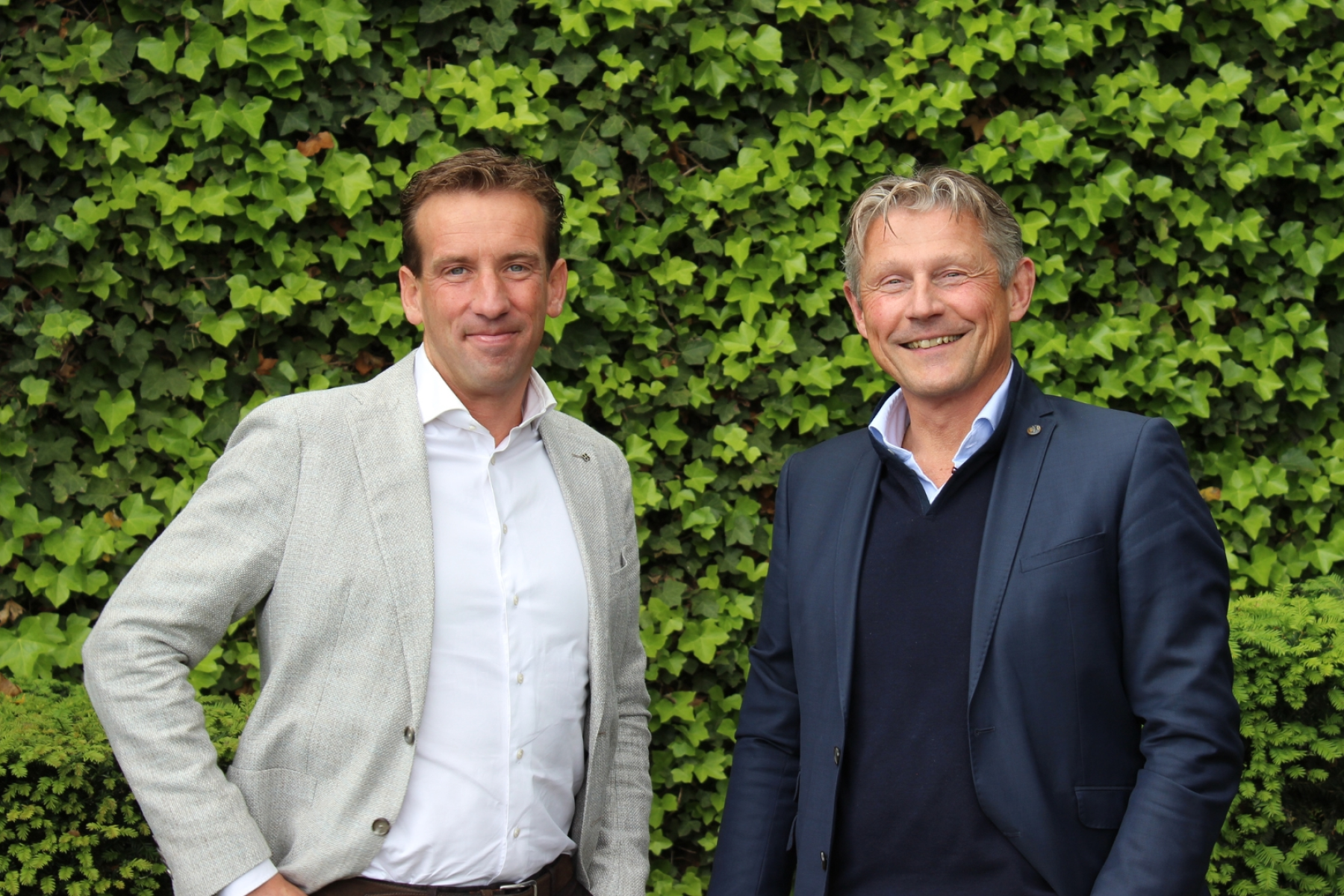 Hilbert Klop und Jan van den Adel stehen vor einer grünen Efeu-Wand