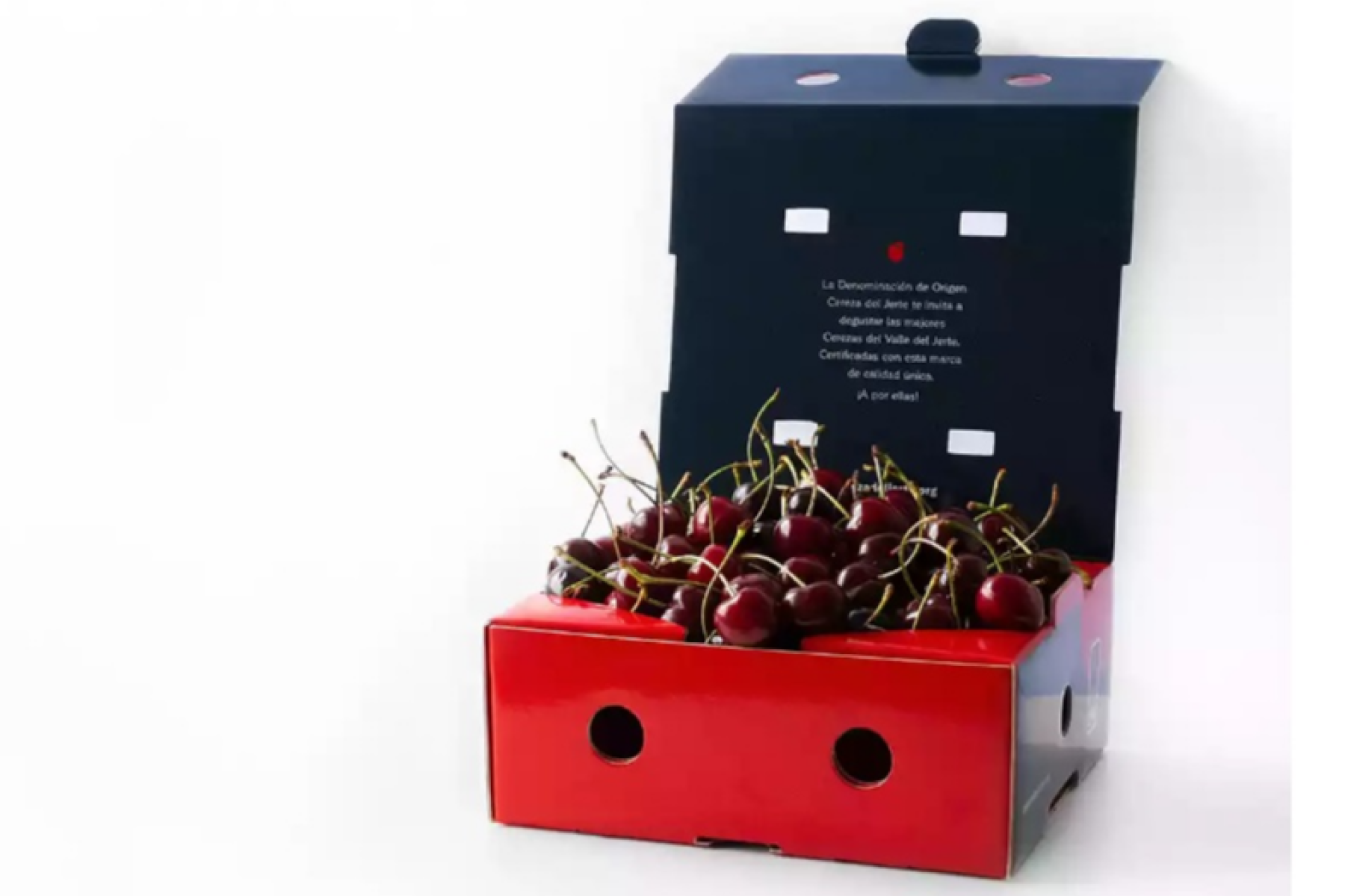 Rote Kirschen in einer offenen, roten und schwarzen Verpackung. Auf der Innenseite der Box steht der Text: 'La Denominación de Origen Cereza del Jerte.'