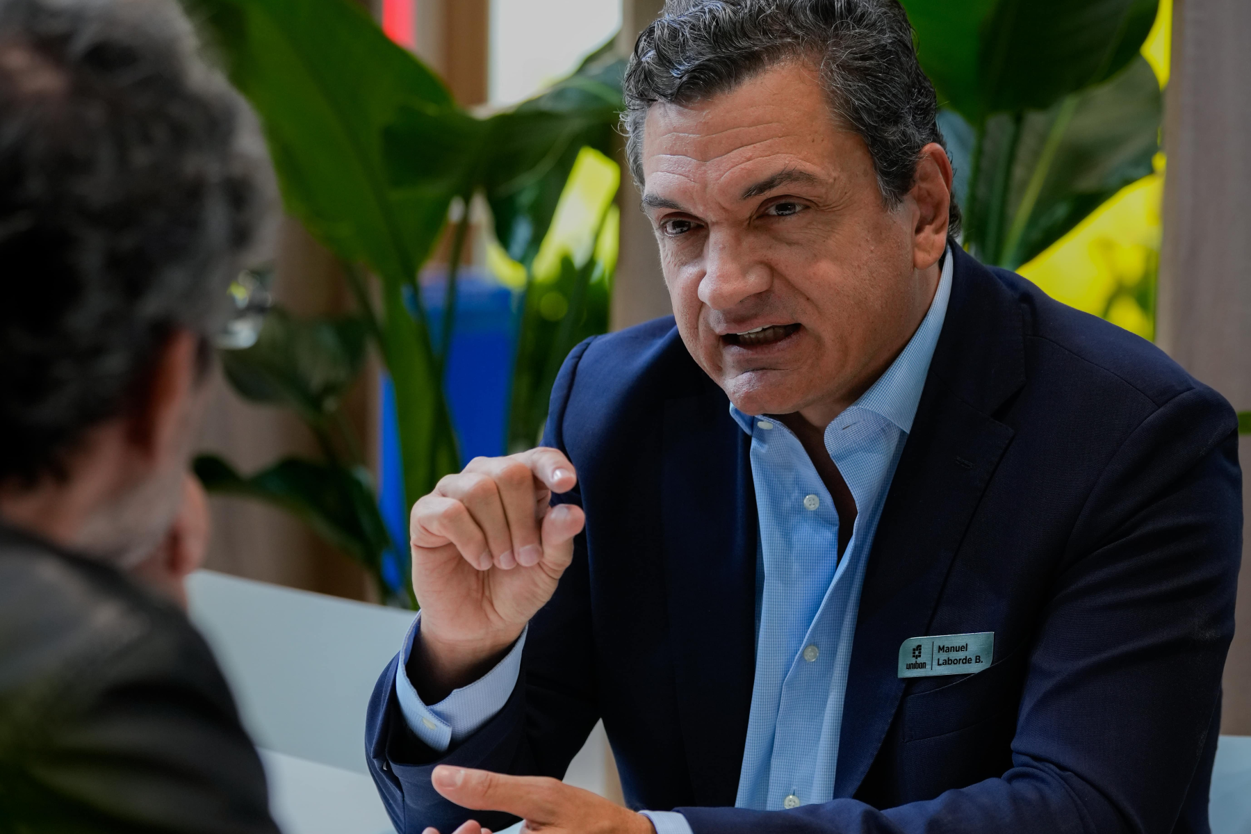 Manuel Laborde Barriga sitzt an einem Tisch, ist im Gespräch und gestikuliert dabei