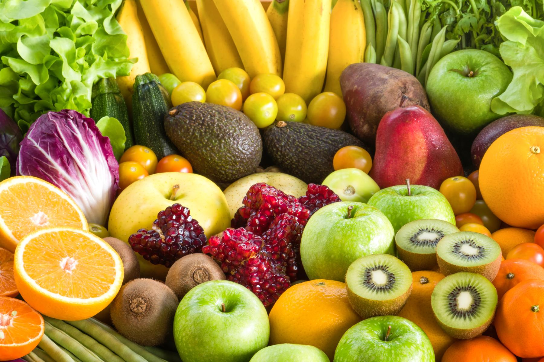Eine Vielzahl von frischem Obst und Gemüse, darunter Bananen, Äpfel, Orangen, Avocados, Kiwis, Granatäpfel und verschiedene Salatsorten.