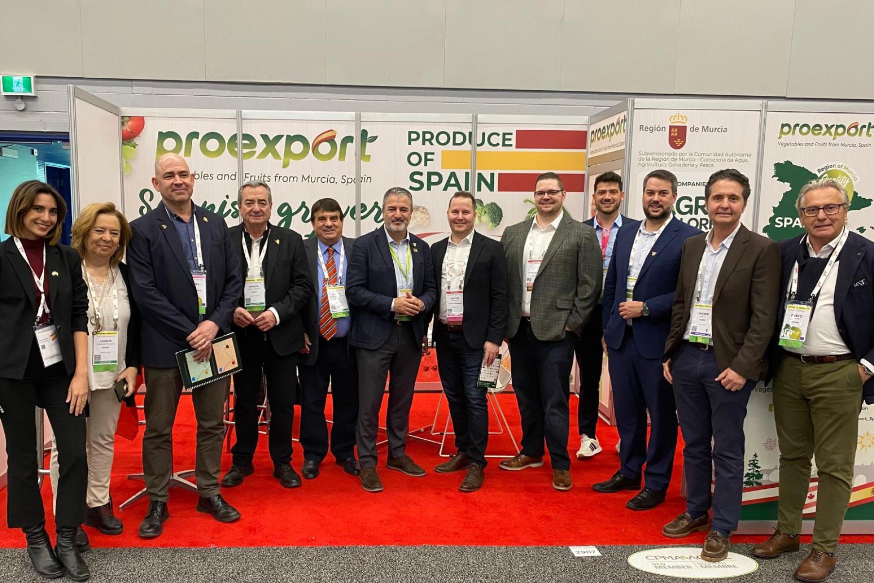 Gruppe von Personen steht vor einem Messestand mit den Aufschriften 'proexport', 'PRODUCE OF SPAIN' und 'Region de Murcia'