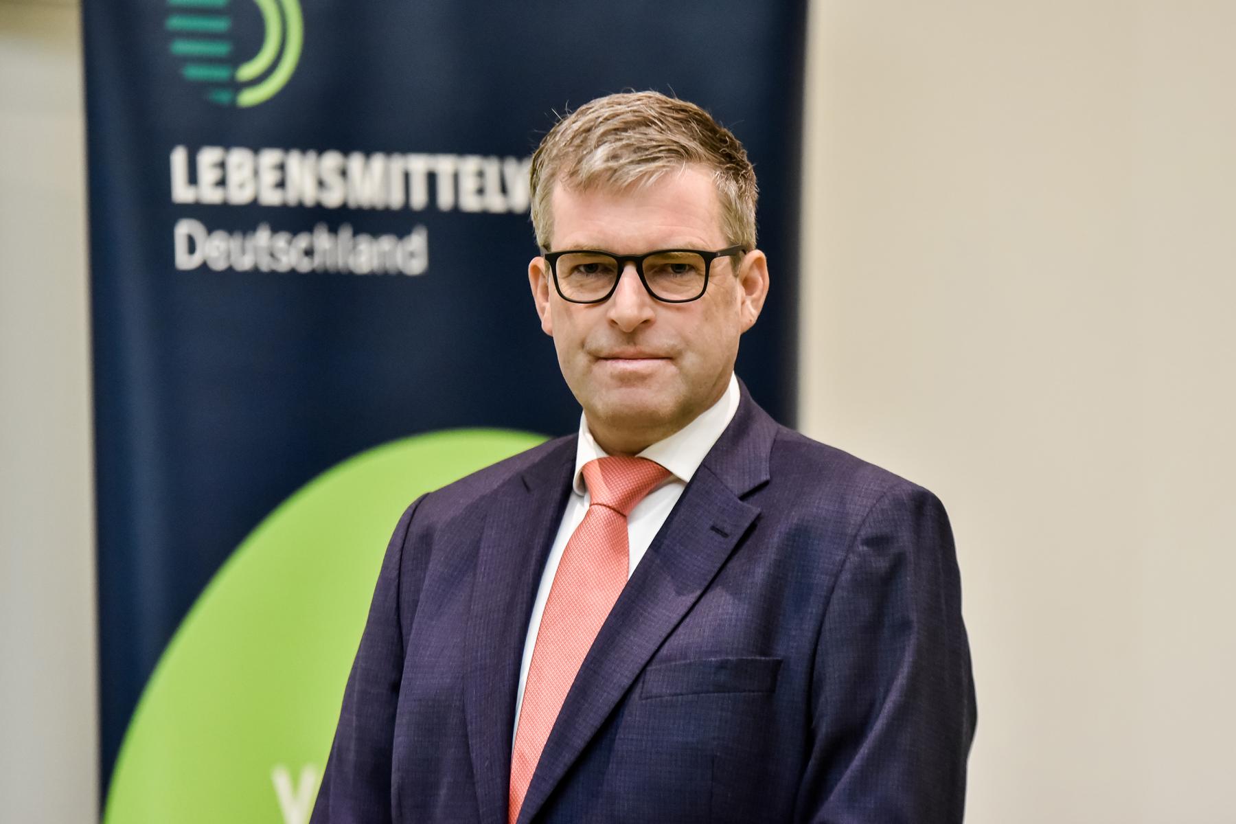 René Püchner steht vor einem Banner mit dem Text 'LEBENSMITTEL Deutschland'.