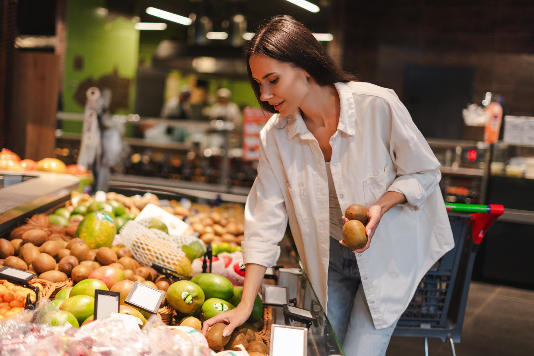 Frau kauft Kiwi im Supermarkt