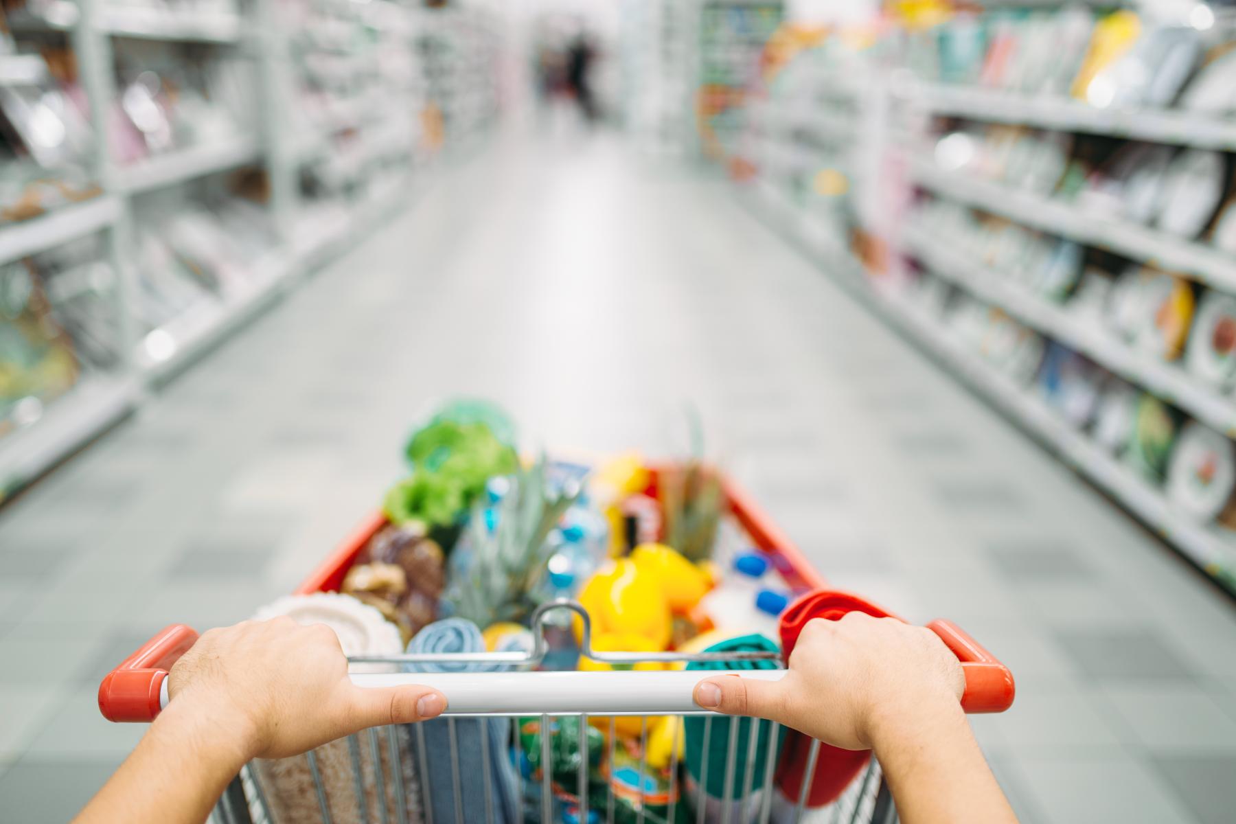 Kunde schiebt Einkaufswagen durch Supermarkt