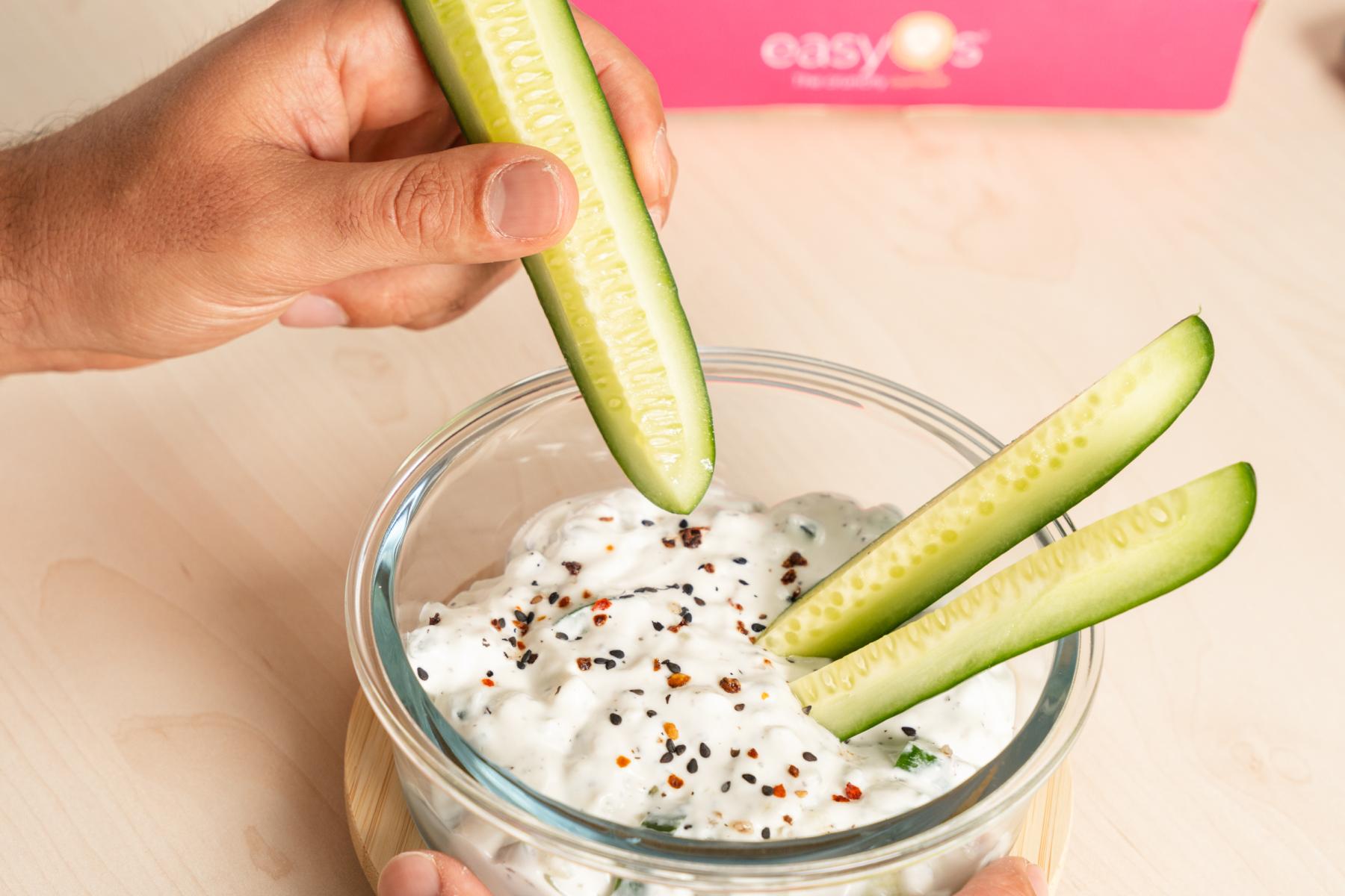 Zwei Hände halten einen Snack mit Mini Gurken