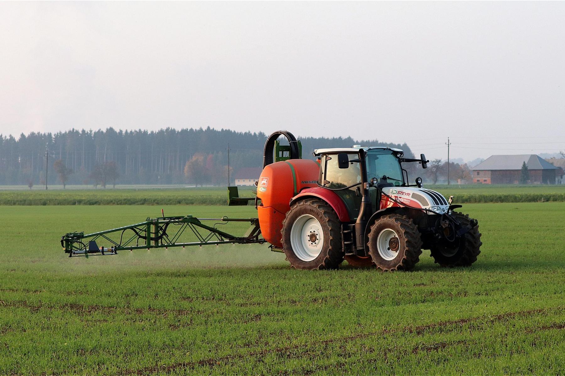 Traktor verteilt Pflanzenschutzmittel auf dem Feld
