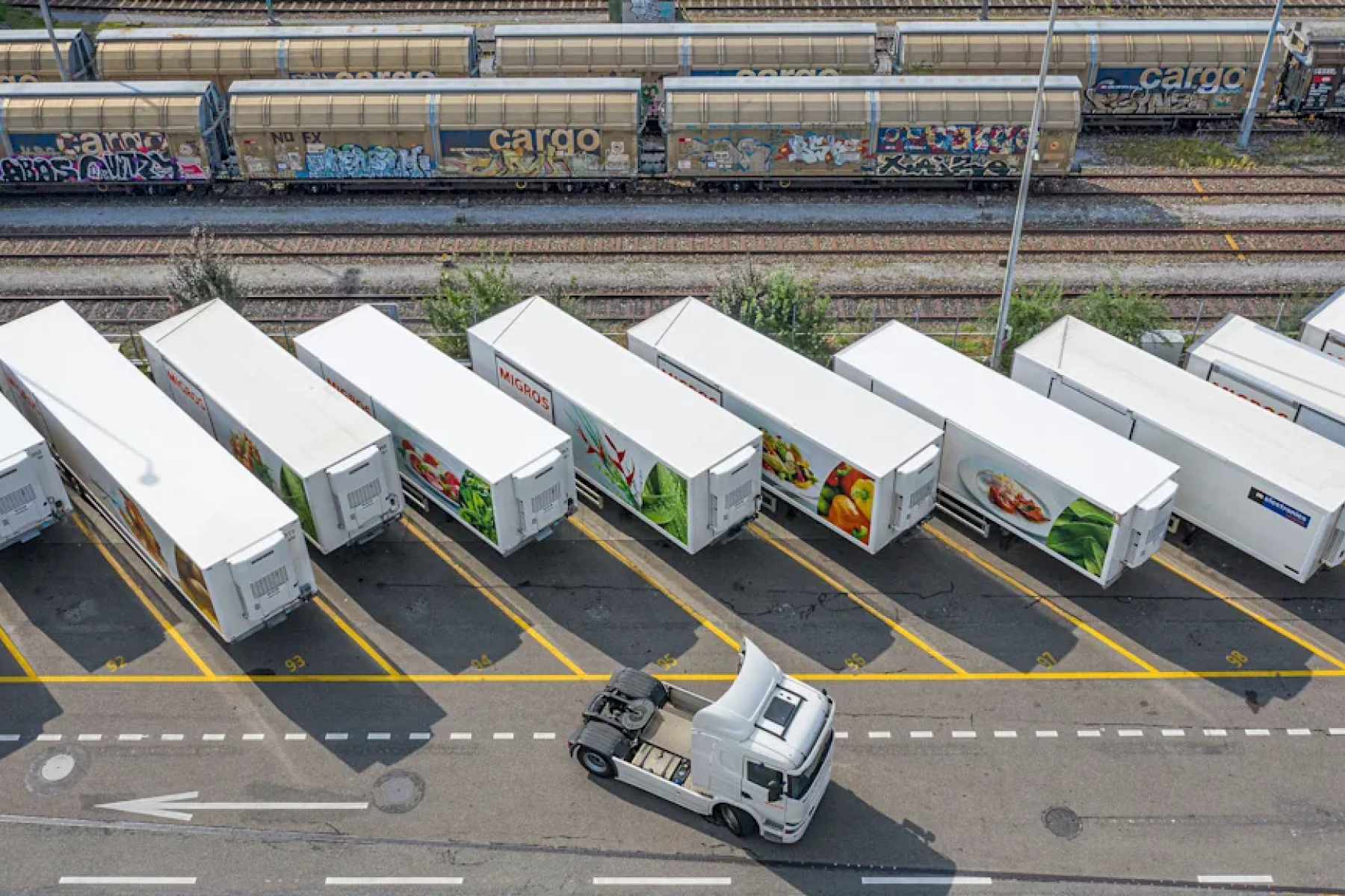 Weiße Kühlcontailer für Obst und Gemüse von Migros warten auf den Abtransport durch Lkw.
