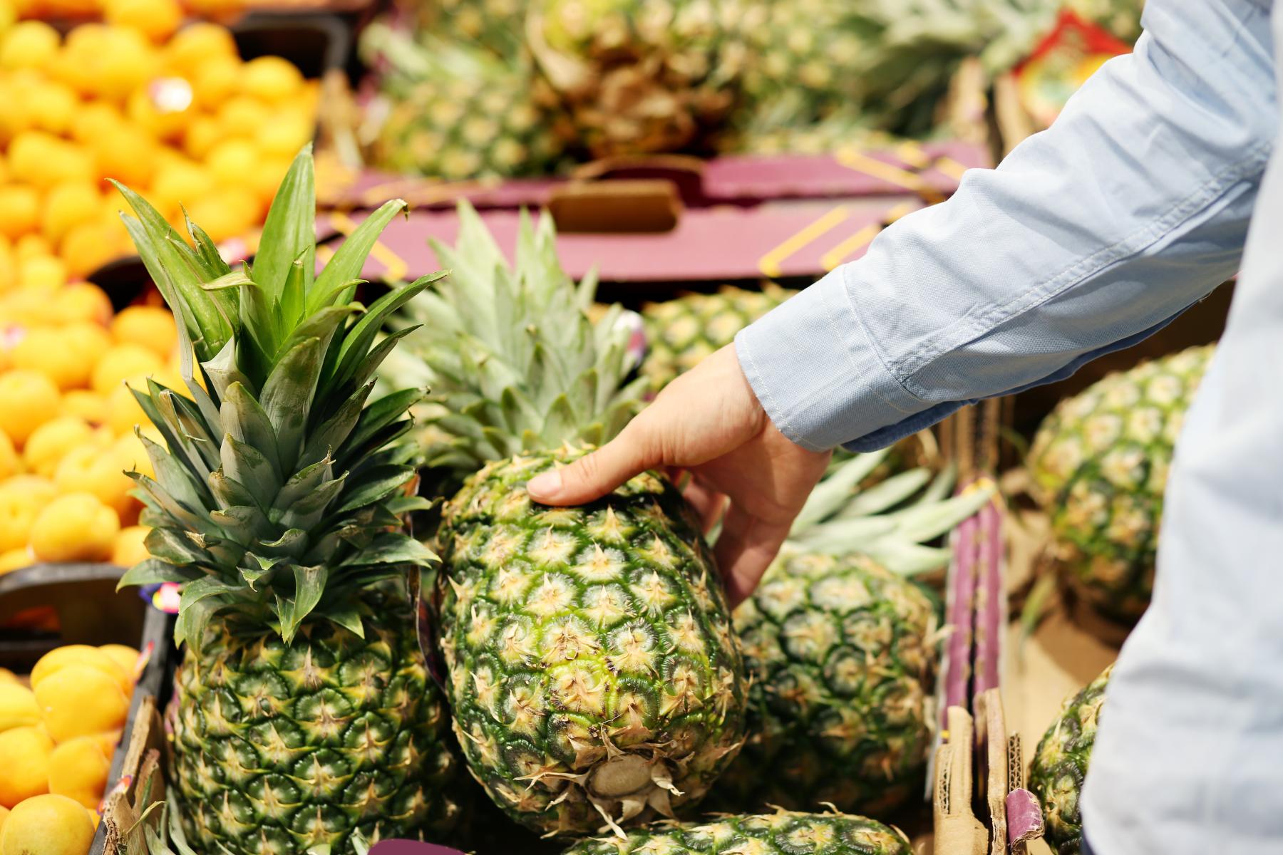 Hand greift nach Ananas im Regal