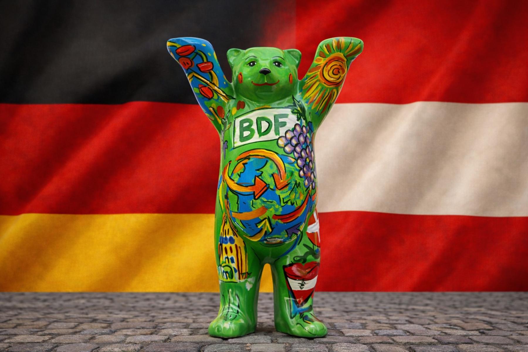 Buddy Bär vor deutscher und österreichischer Flagge