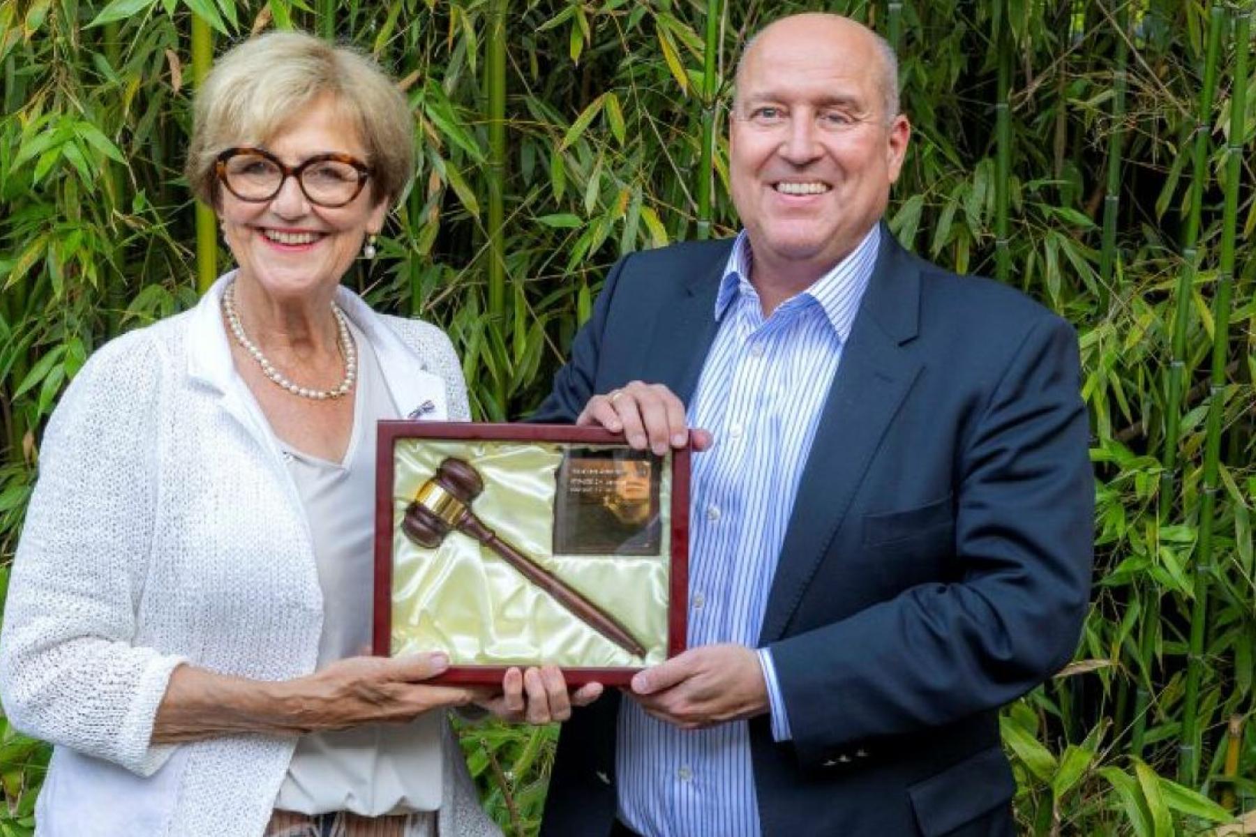 Mann und Frau halten Bilderrahmen mit Holzhammer in der Hand