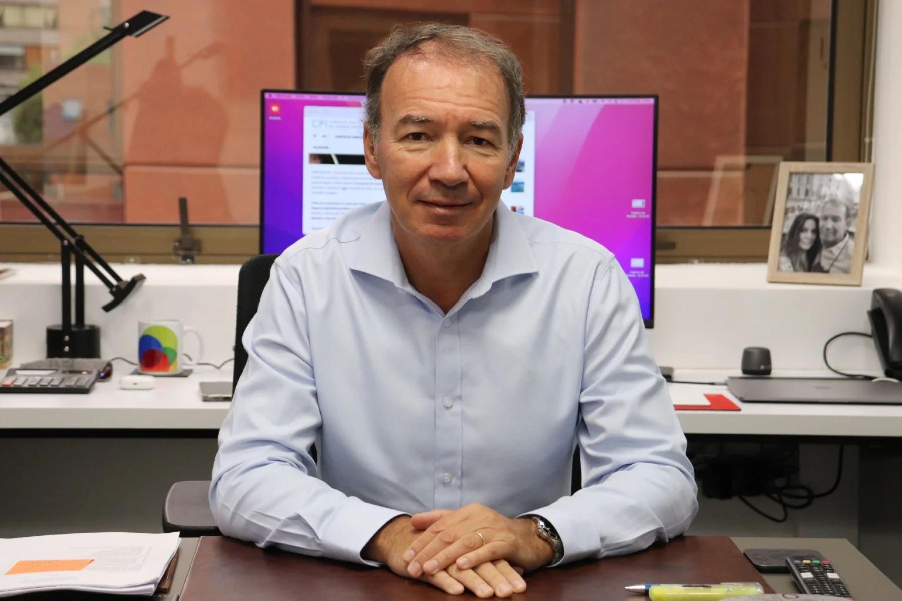 Mann sitzt an Schreibtisch mit Computer im Hintergrund