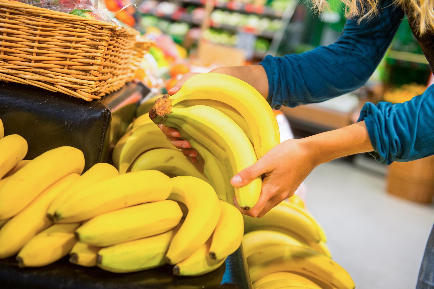 Hände greifen im Supermarkt nach Bananen