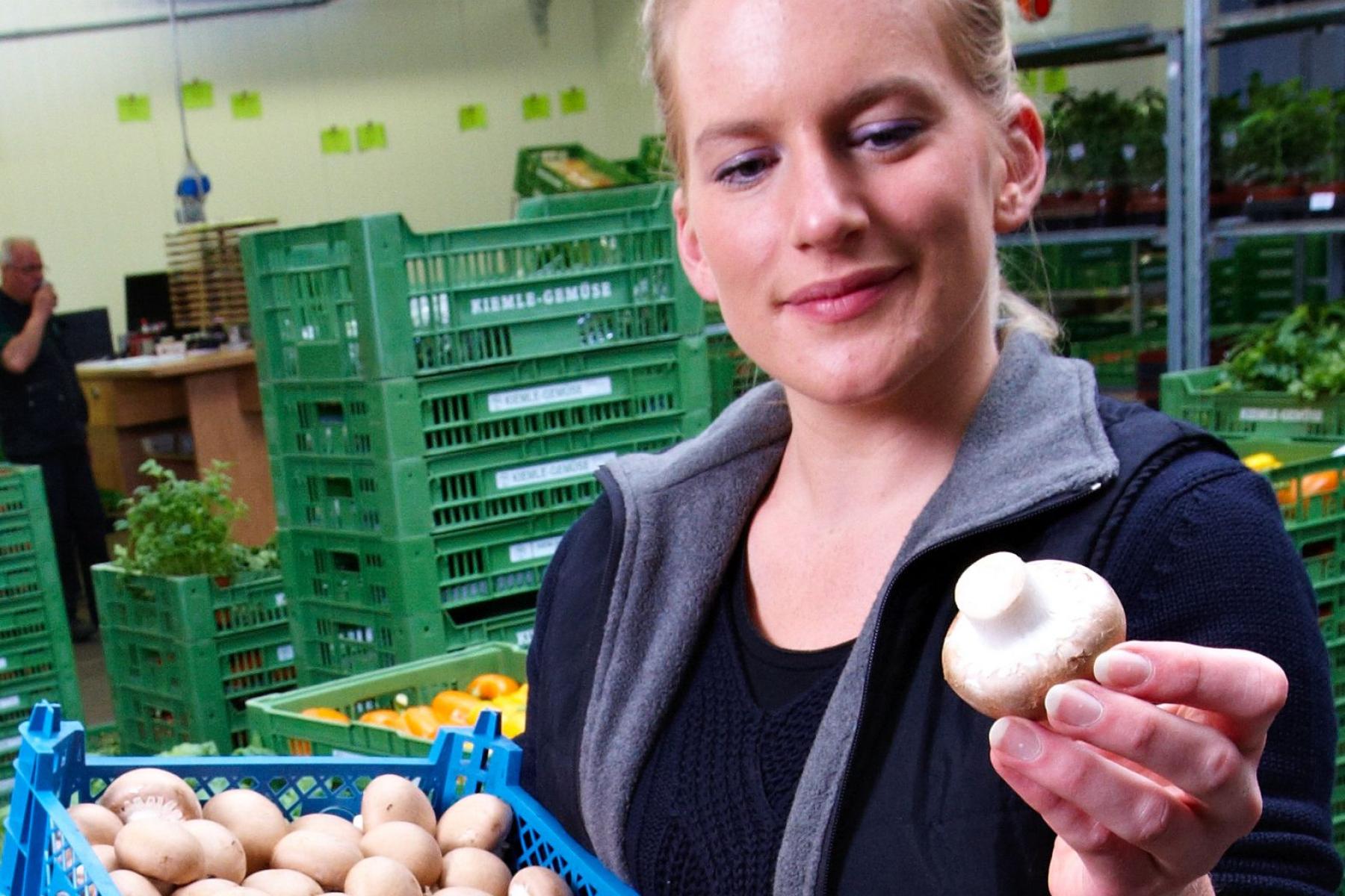 Frau hält Kiste mit Champignons in der Hand