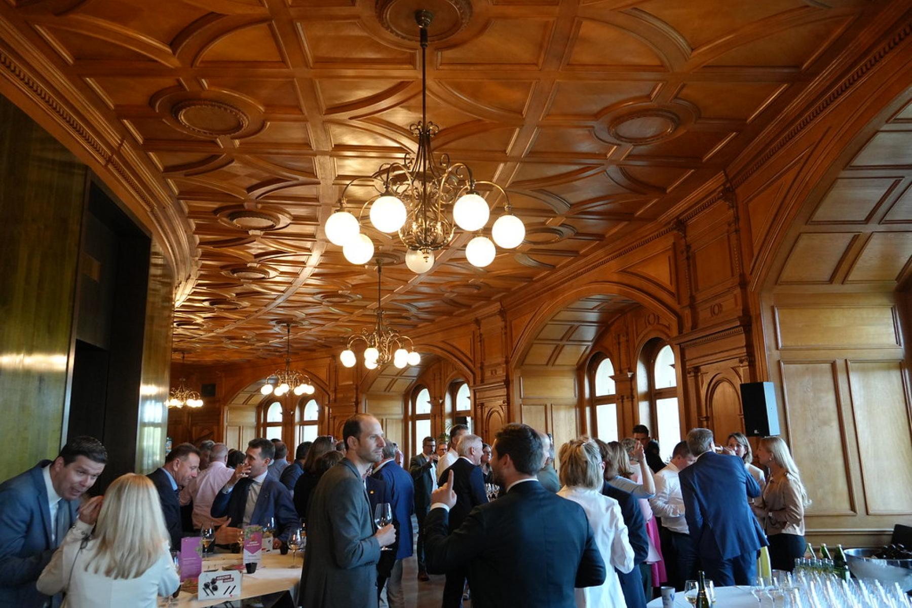 Menschen in altem Saal mit Getränken in der Hand