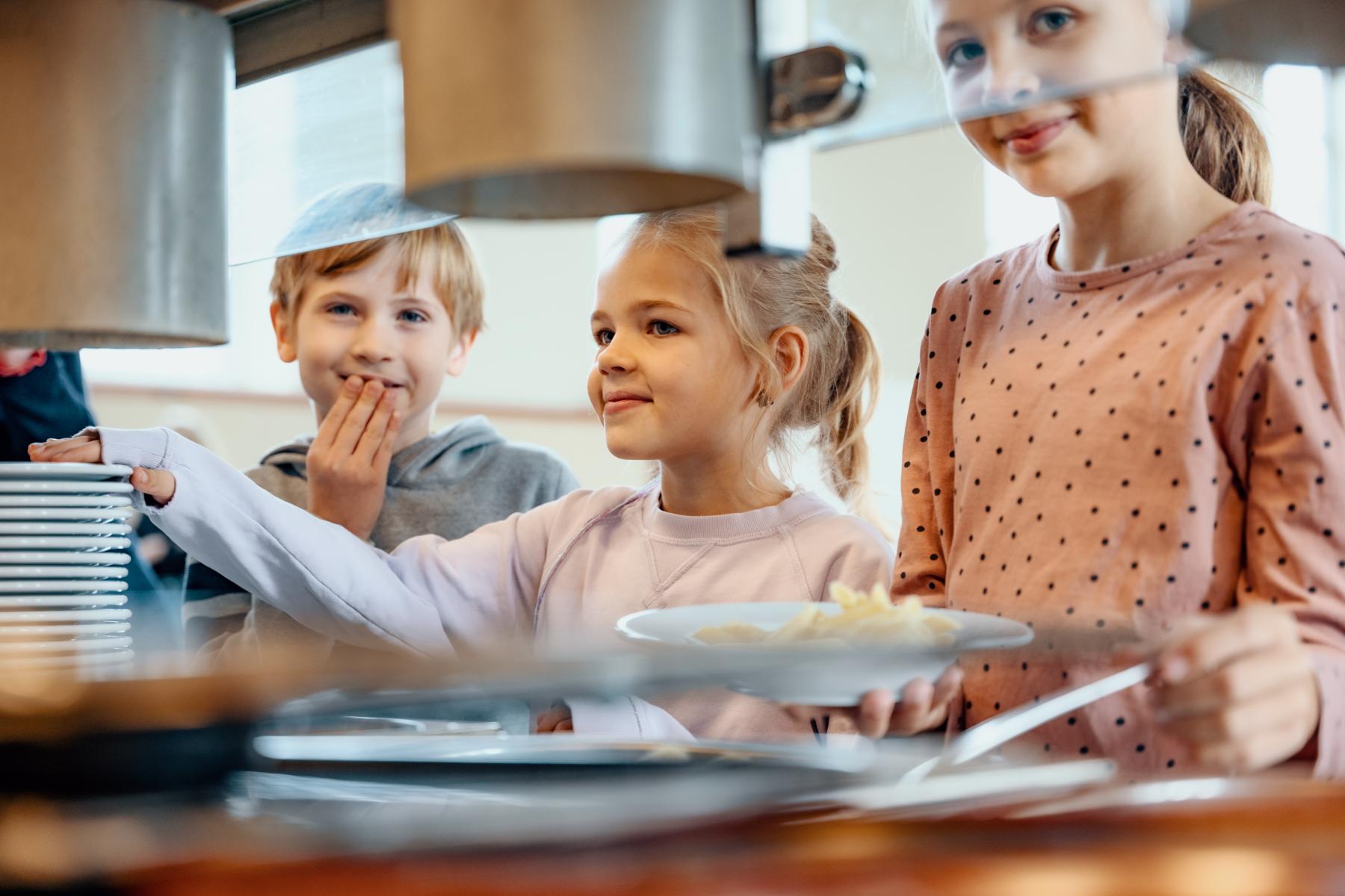 Kinder stehen an Bedientheke für Essen