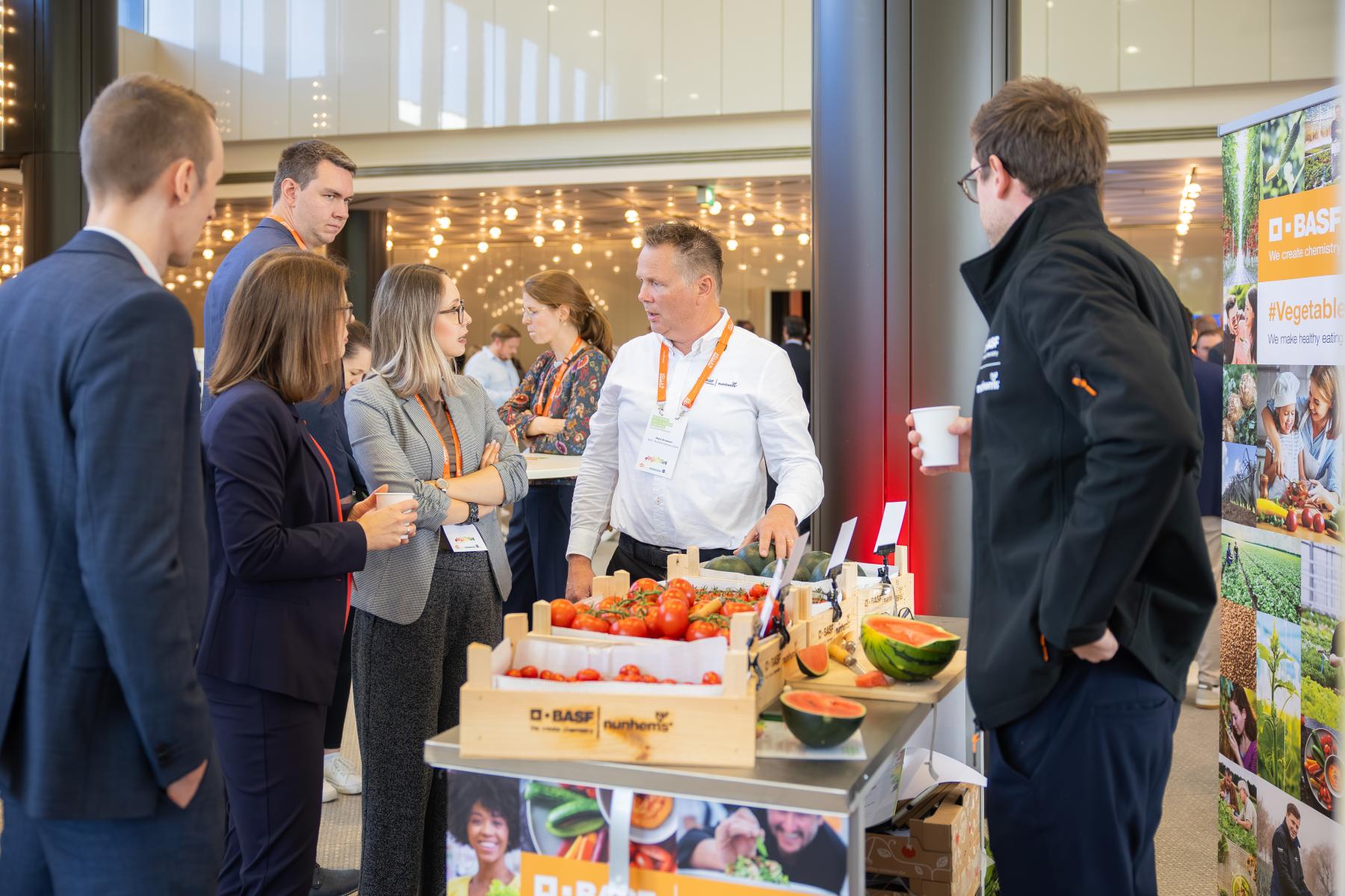 Personen stehen um Tisch mit Obst und Gemüse und sind im Gespräch