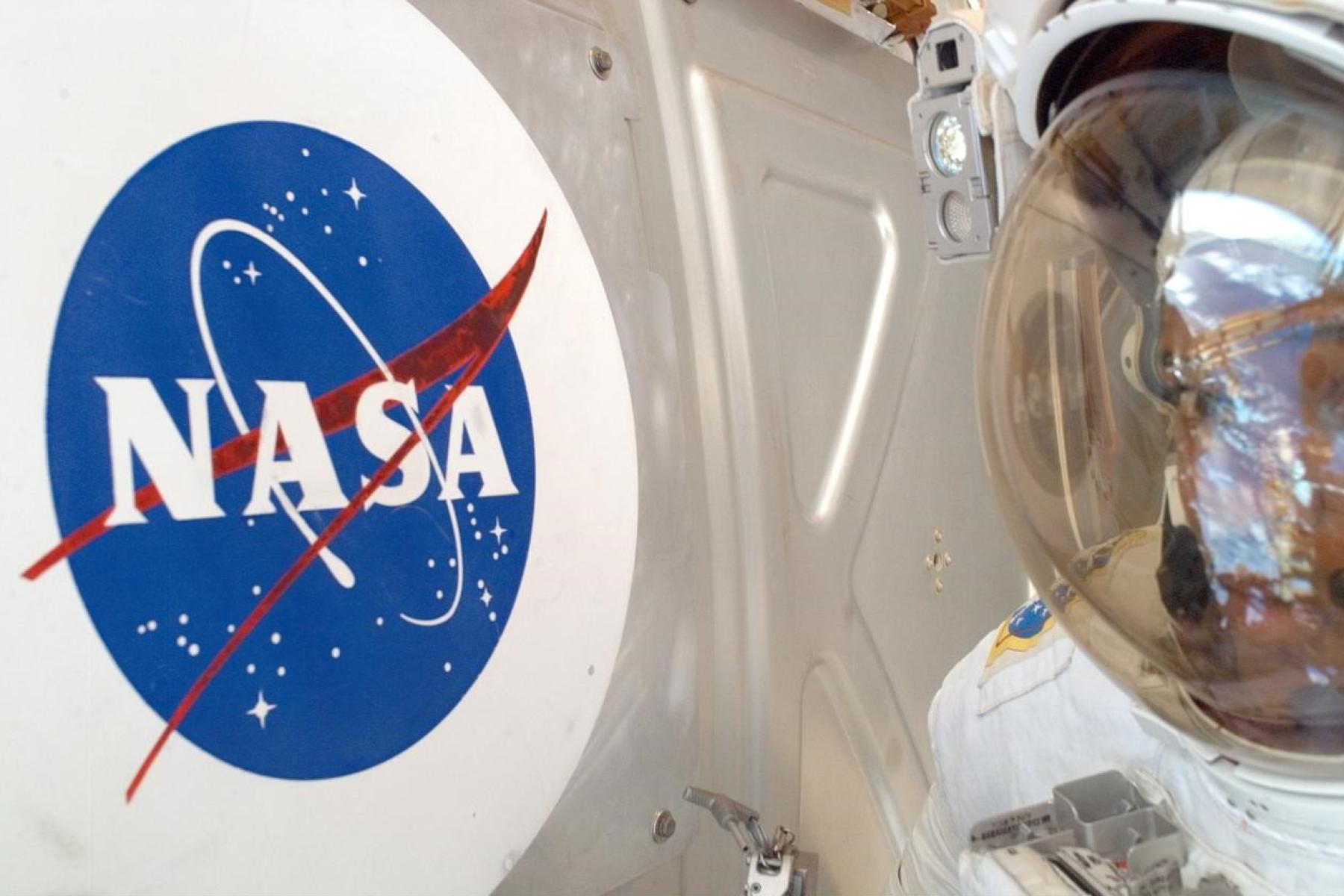 Der Helm eines Astronauten neben dem NASA-Logo.