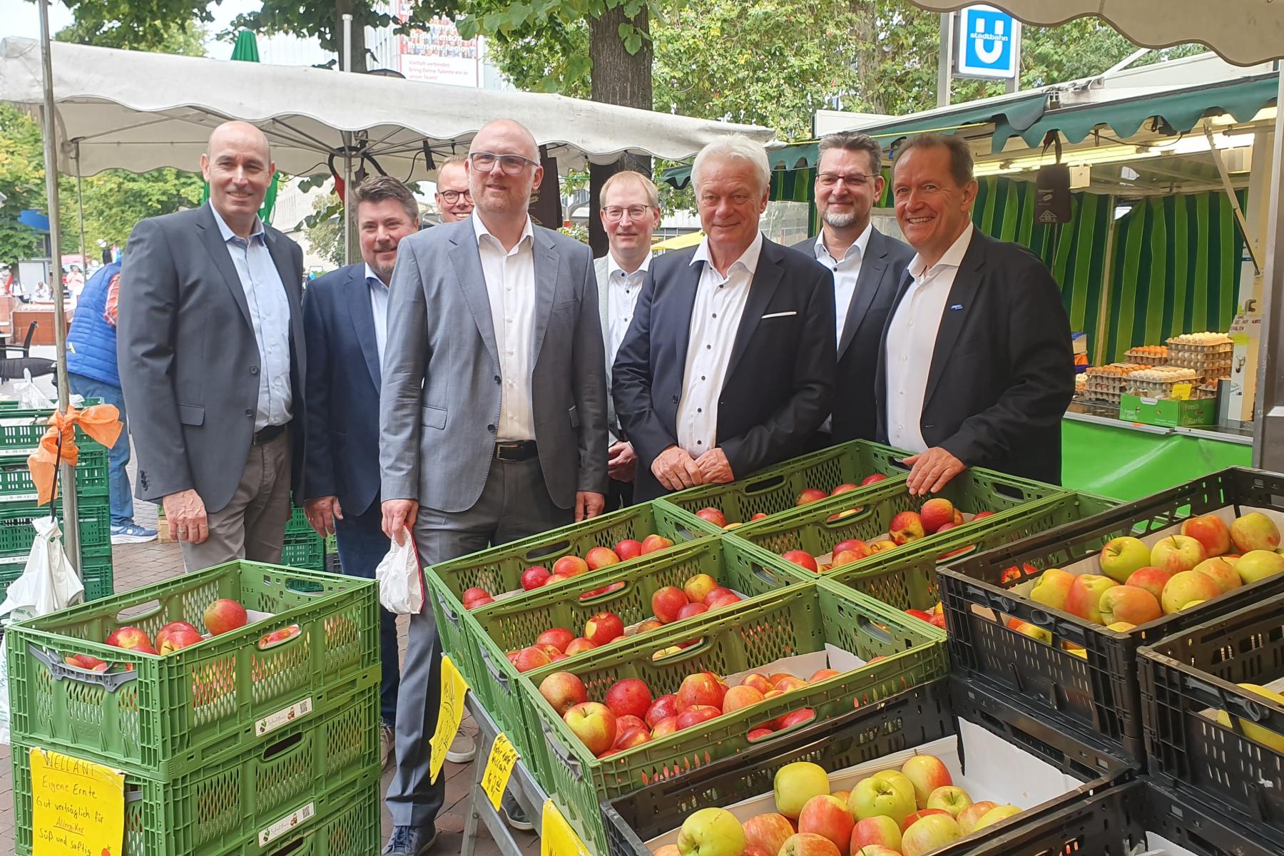Männer stehen an einem Marktstand vor Äpfeln