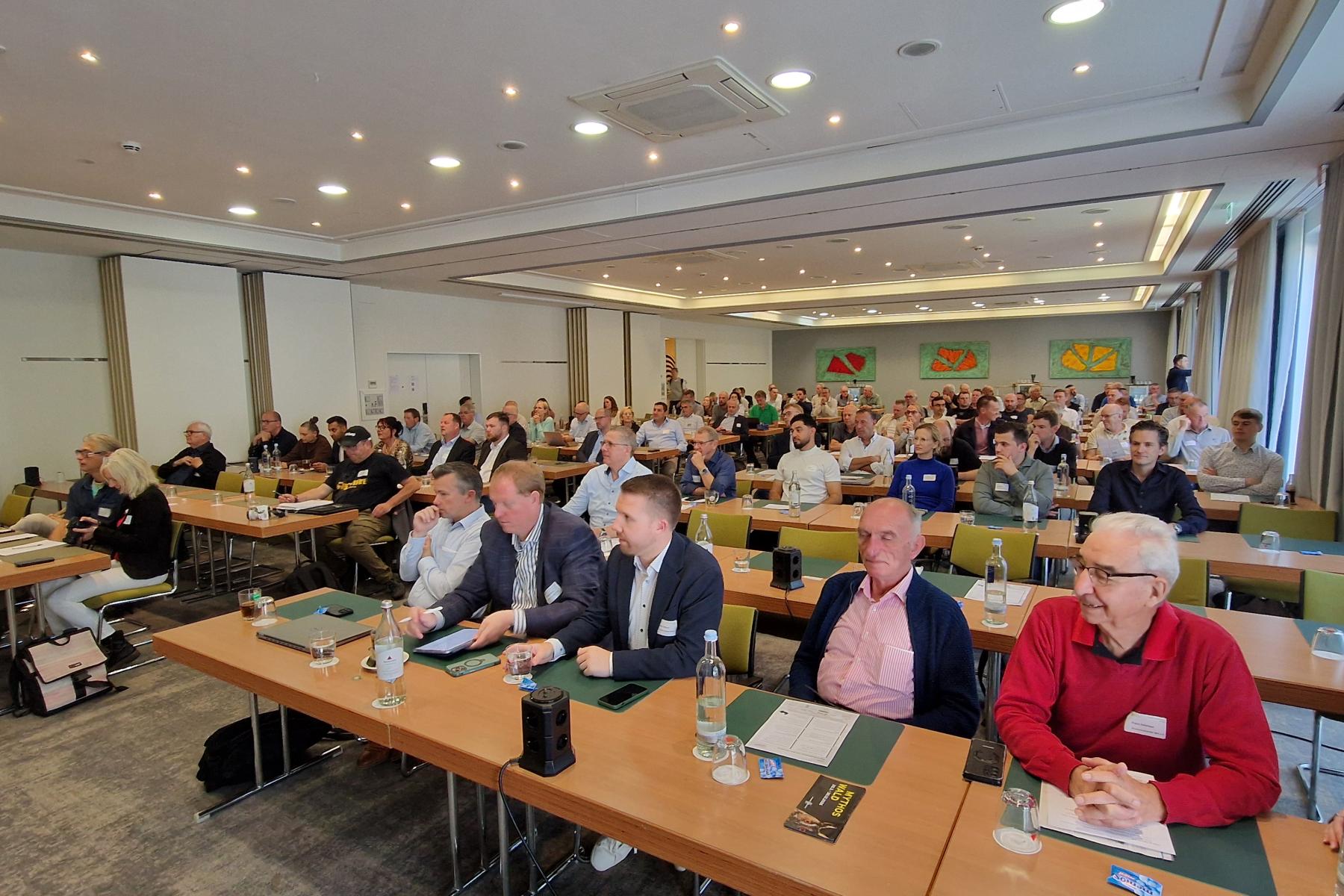 Zahlreiche Teilnehmende sitzen während einer Fachtagung in einem großen Konferenzraum.