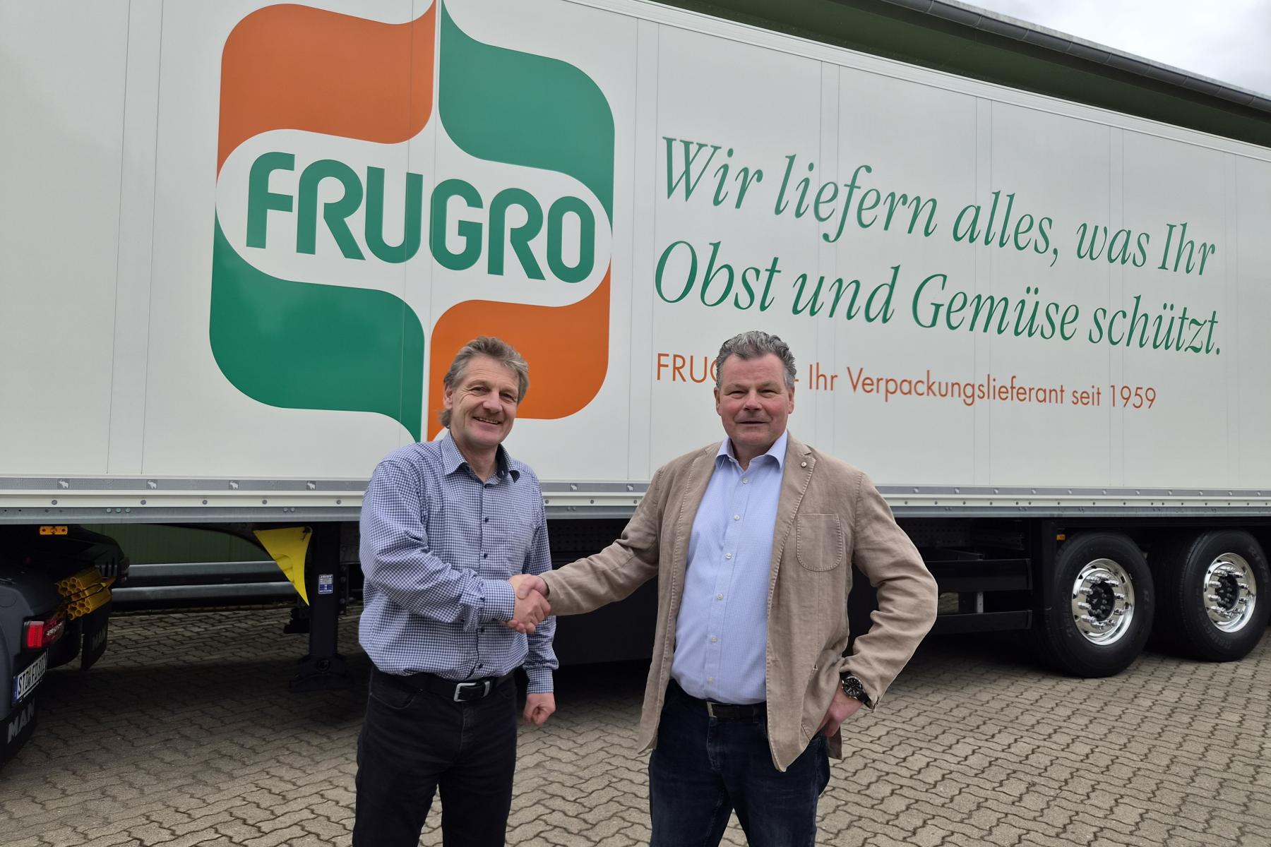 zwei Männer schütteln die Hände vor einem Lkw