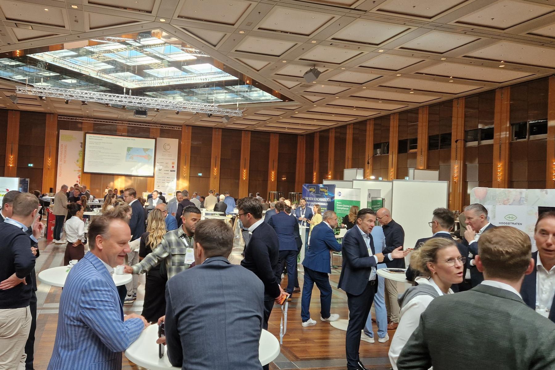 Teilnehmende des Deutschen Obst- und Gemüsekongresses (DOGK) 2026 im Veranstaltungsraum in Düsseldorf im Gespräch an Stehtischen und Ausstellerständen.